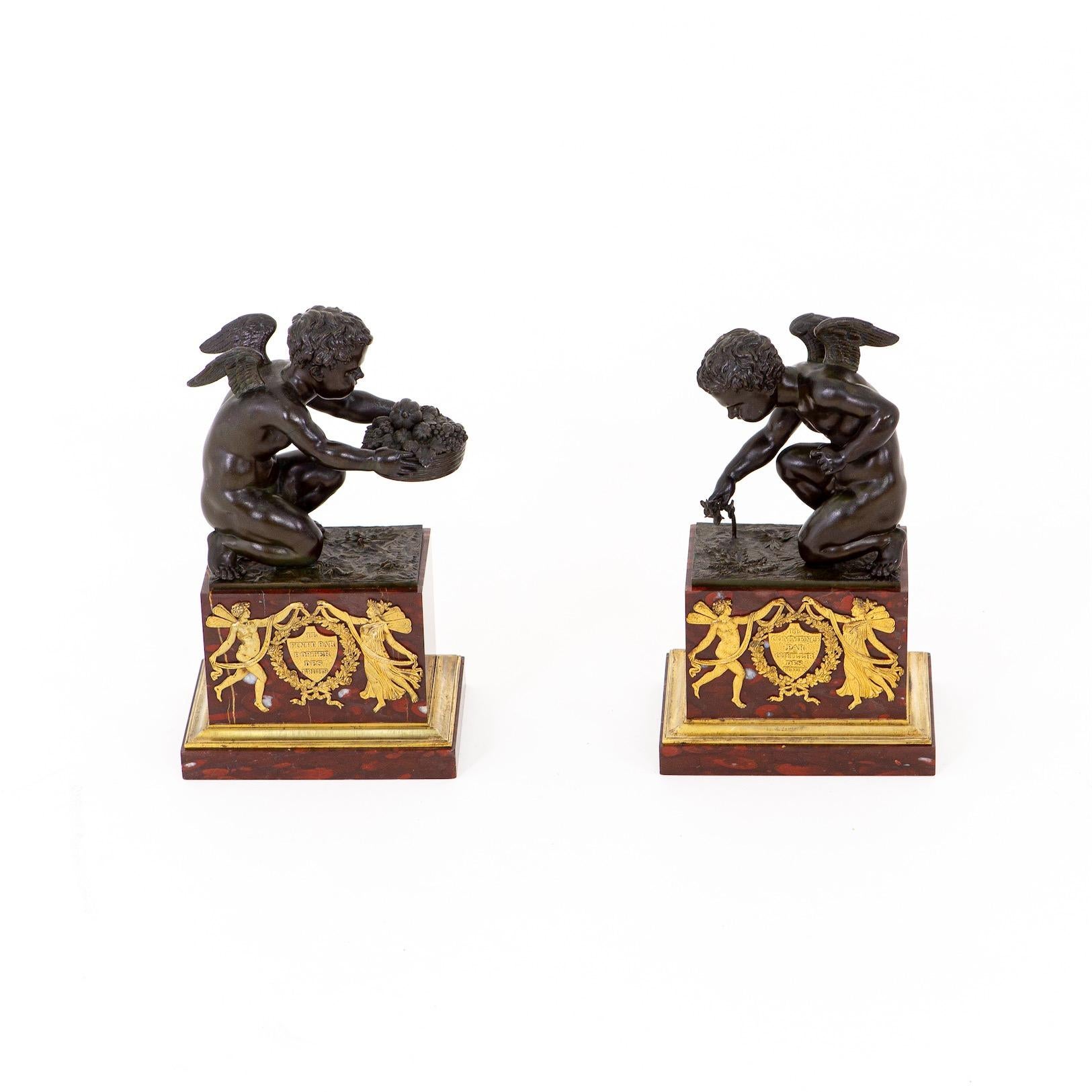 Pair of putti as personifications of two lovers on marbre griotte bases. Bronze burnished and gilded. Inscribed in cartouches on the fronts 'Il Finit Par Porter Des Fruits' and 'Il Commence Oar Cueillir Des Fleurs' and surrounded by winged male and