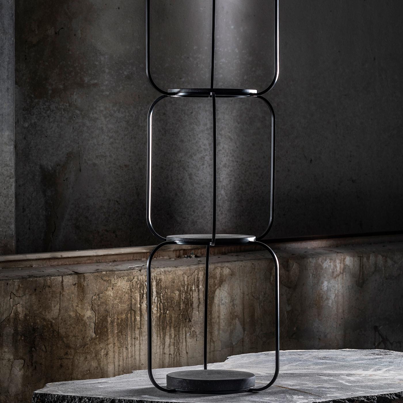 Part of the Tarsie Geometriche collection, this bookcase is a sculptural masterpiece. Varnished with an opaque black powder, the linear iron structure creates a striking silhouette with four black tops made of volcanic stone with a honed finish,