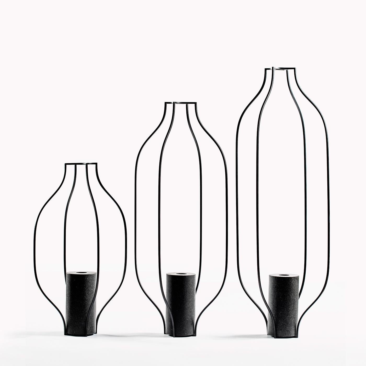 Eisen und Naturstein vereinen sich zu einer laternenartigen Vase, die durch ihre Vertikalität besticht. Dieses Stück aus der Kollektion Tarsie Geometriche besteht aus undurchsichtigen, schwarzen Eisenstäben, die eine zylindrische Vase aus schwarzem