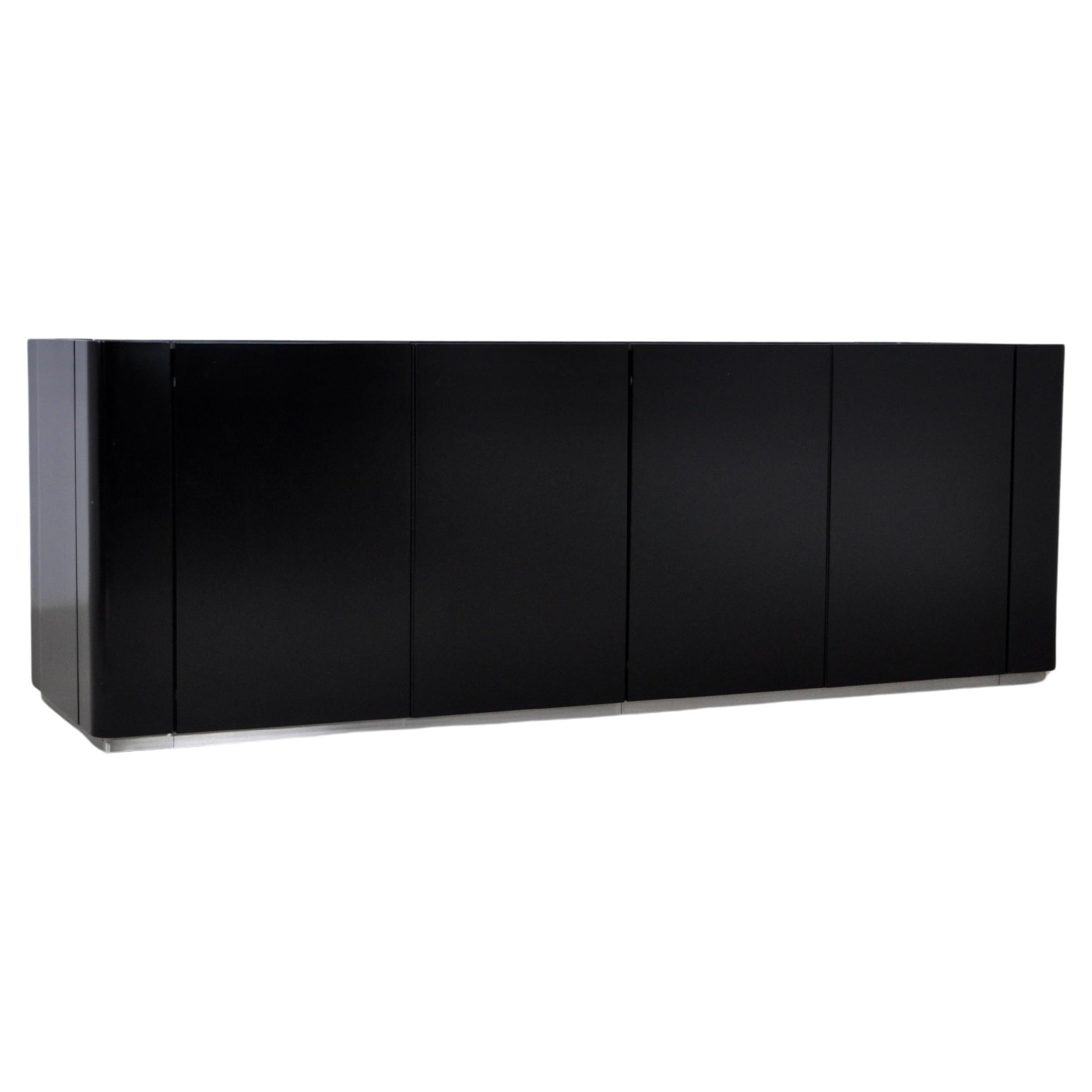Black wooden sideboard with a mirror on top and a metal bar on the bottom. 4 doors with two drawers and two shelves inside. Wear due to time and age of the sideboard.