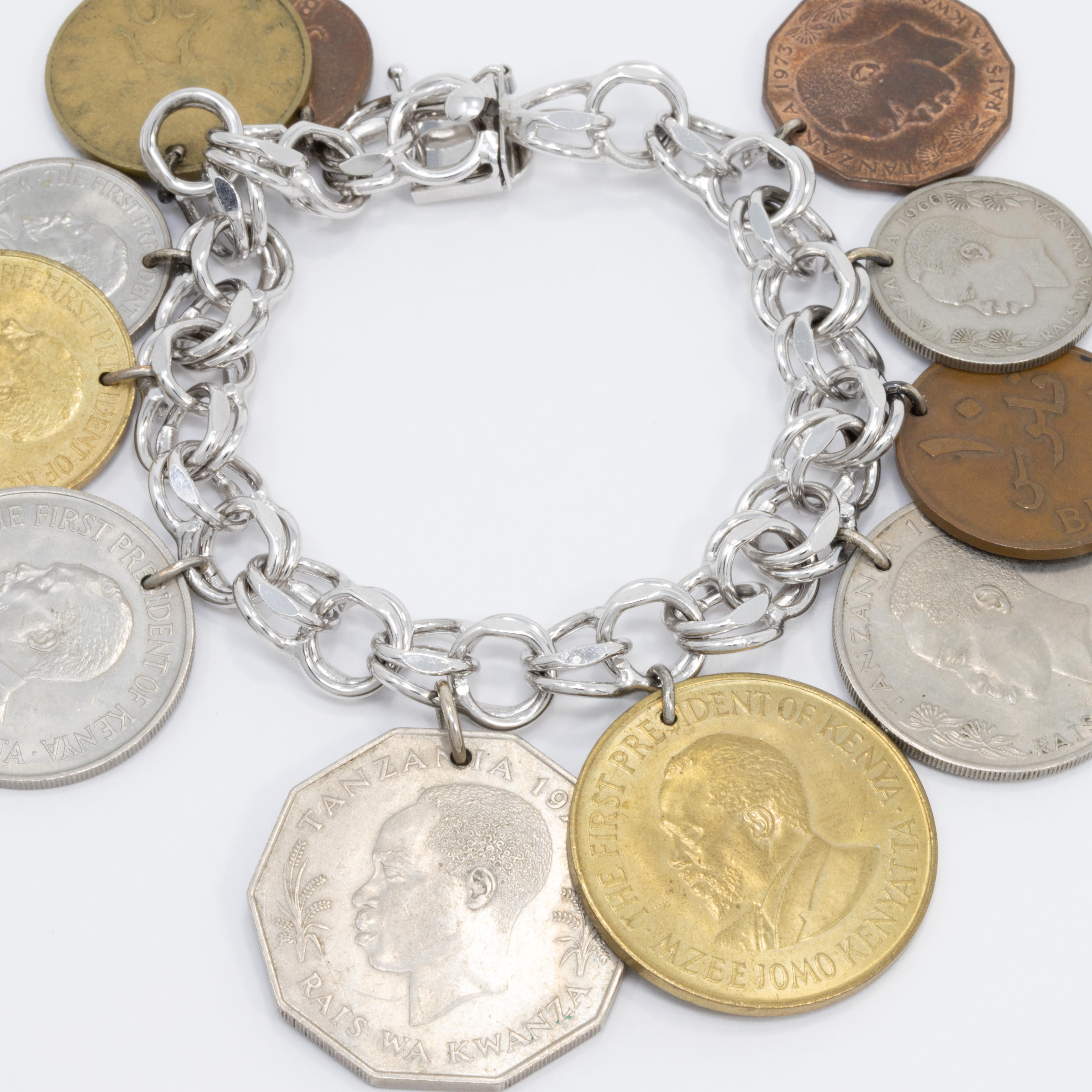 Sterling silver chain bracelet from Eton, featuring dangling African coin charms from Tanzania, Bahrain, and Kenya.

Box clasp closure.

Marks/hallmarks: Sterling, Eton