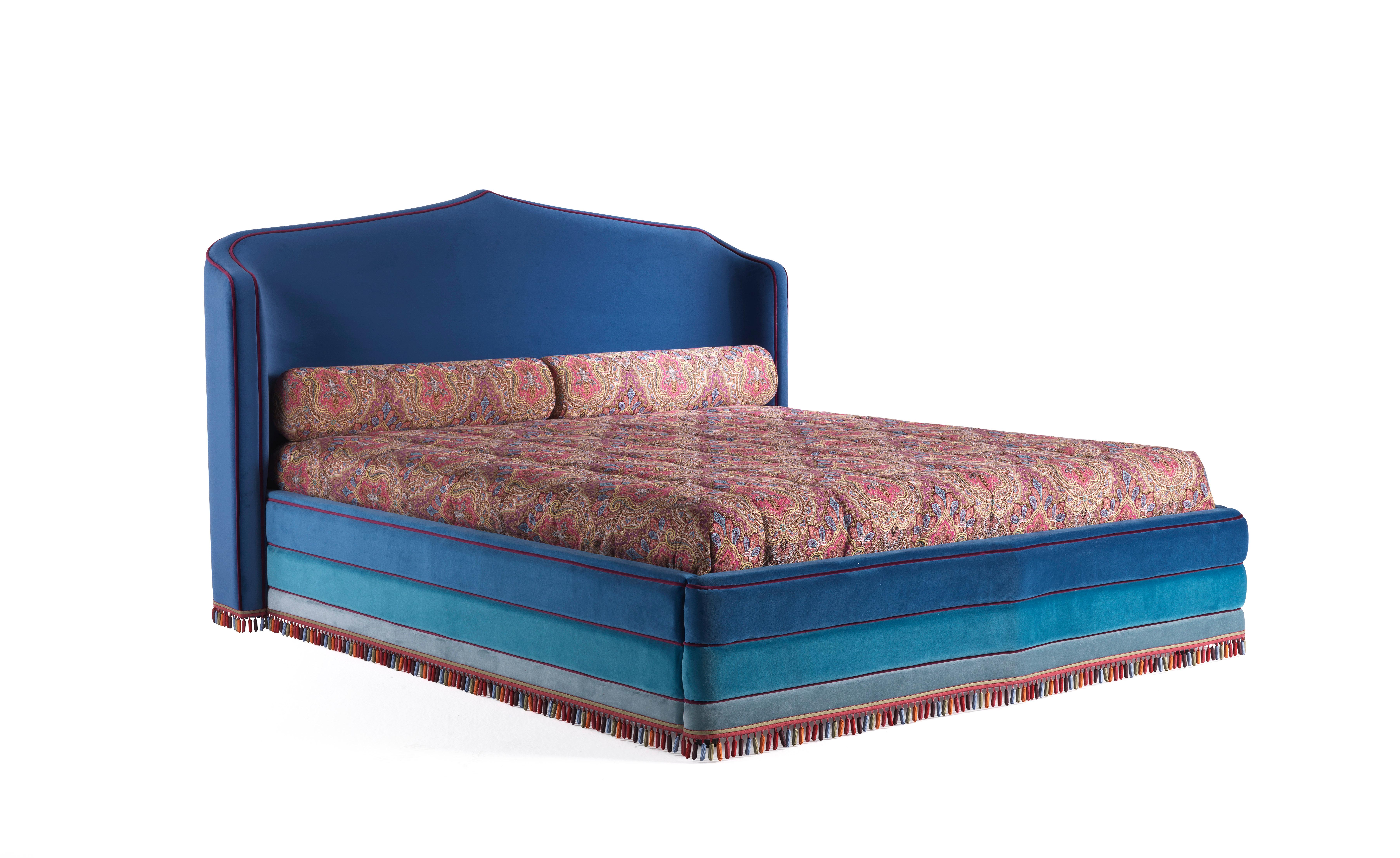 A fairy-tale bed inspired by a ‘thousand-and-one-nights’ imagery. The arabesque shape of the headboard, the intense turquoise color with purple piping and the precious and the multicolor passementerie contribute to creating a magical and