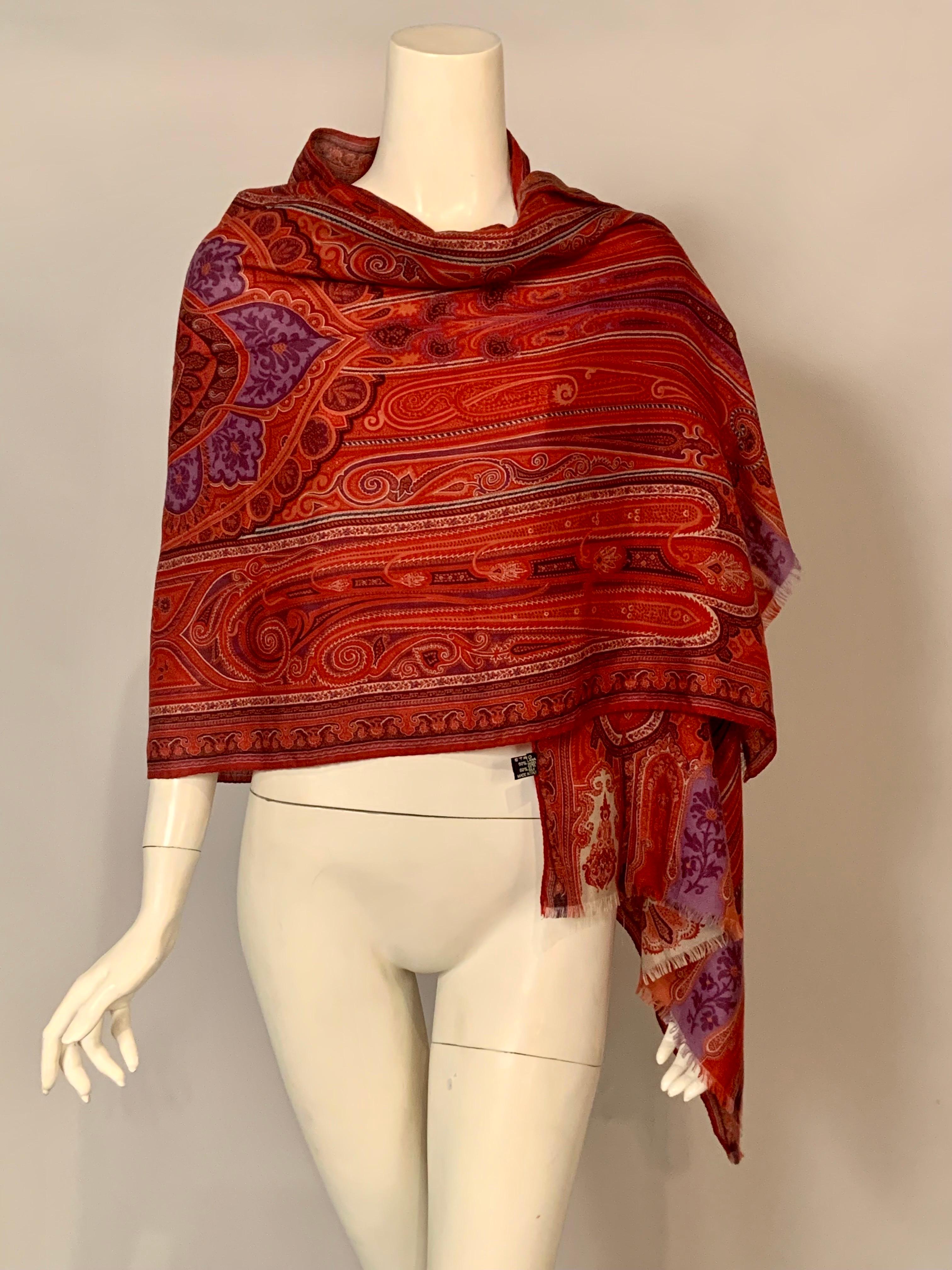 A very  colorful paisley pattern  scarf from Etro, Milan is made from wool and silk.  The scarf is predominately shades of red with cream, blue and black.  The center of the scarf has designs worked in lavender and purple creating a more