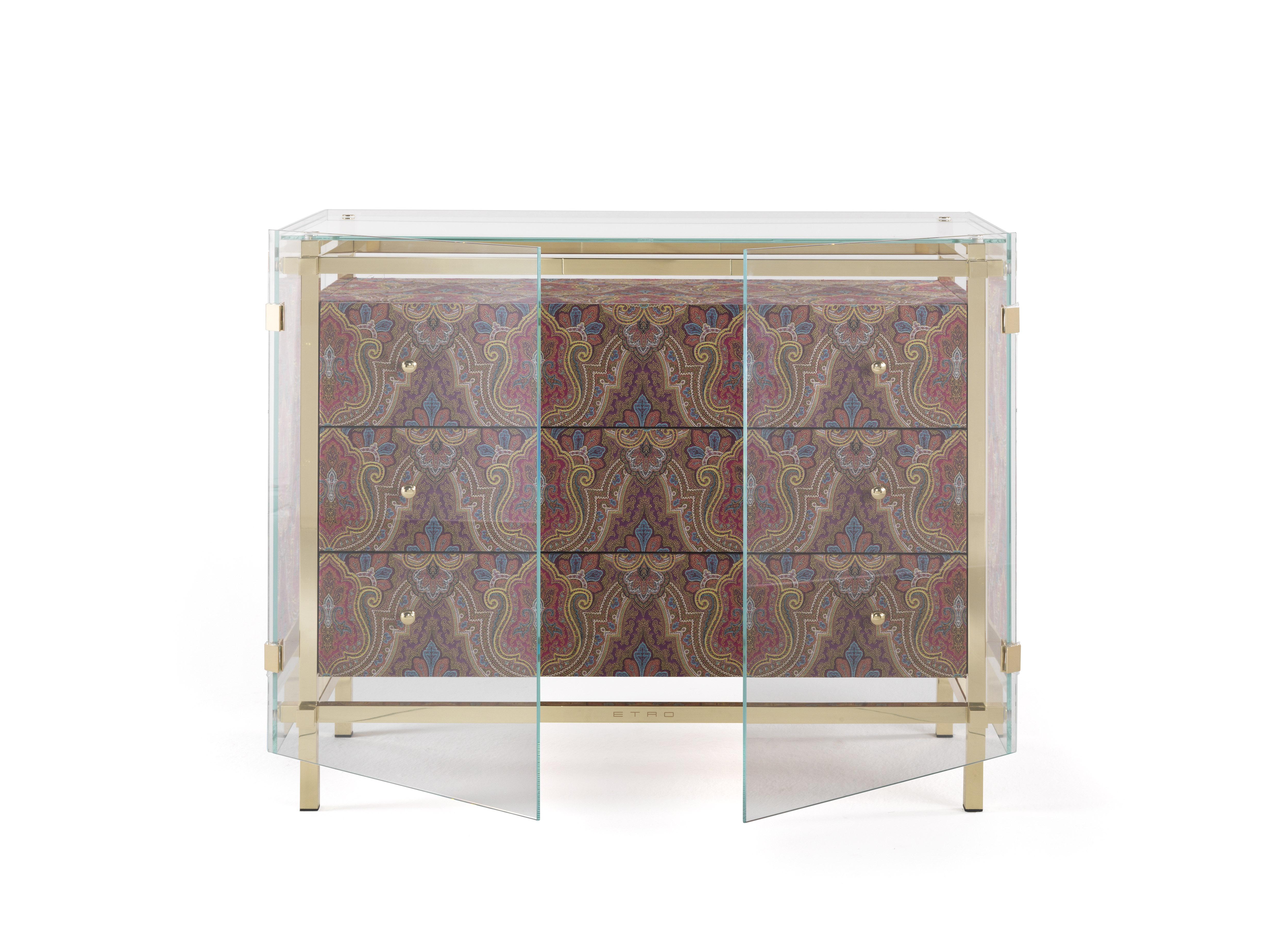 An impactful chest of drawers featuring a precious upholstery in fabric from the Etro Home Interiors collection with oriental inspired decorative motives and outer extraclear tempered glass. A mystic and transcendent element with an ethereal and