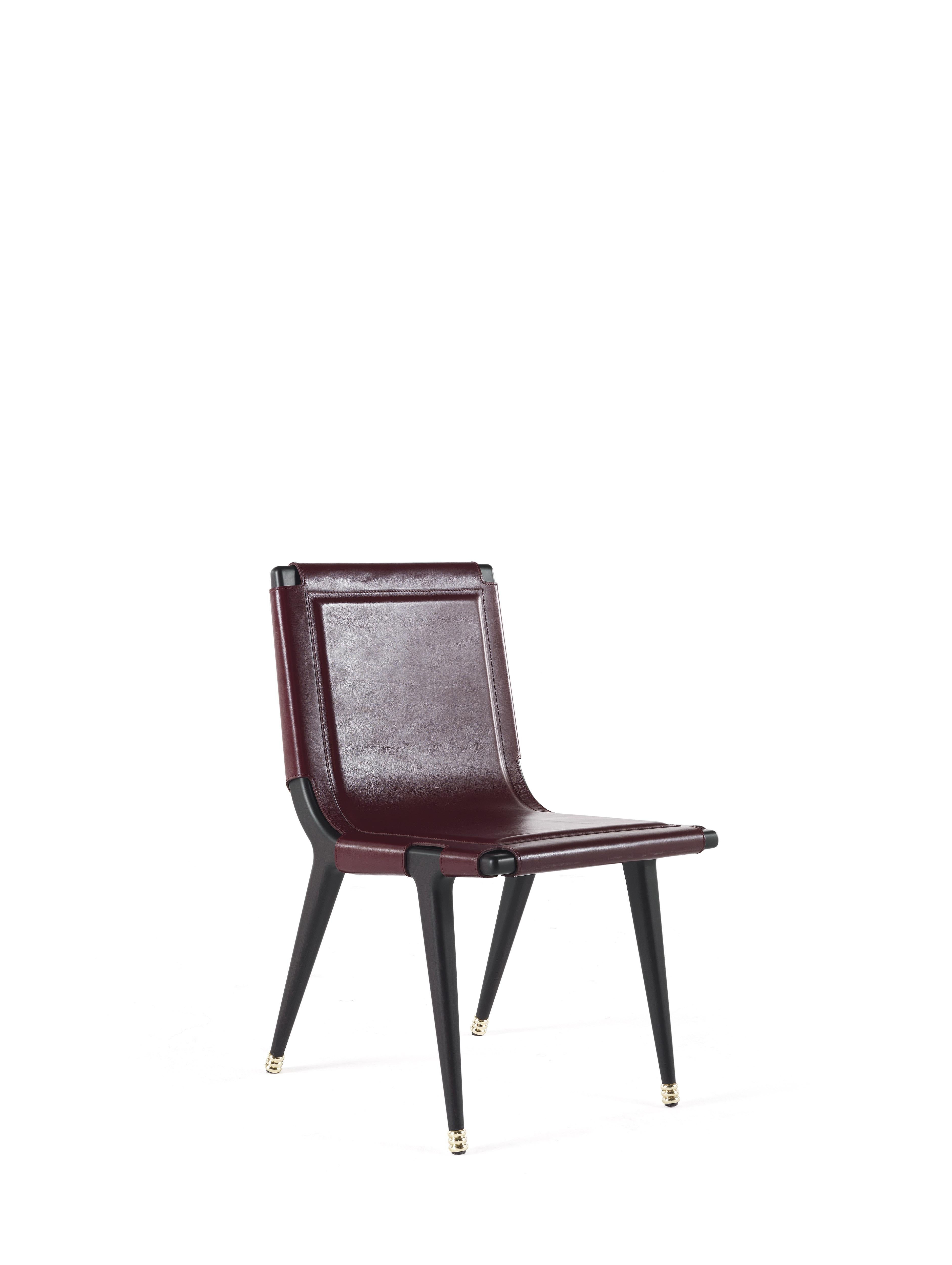 A chair full of fascinating details and evocative references. The precious upholstery in cherry color leather features a special rope binding with polished brass details on the back, while the structure in matte dark wengè wood with polished brass