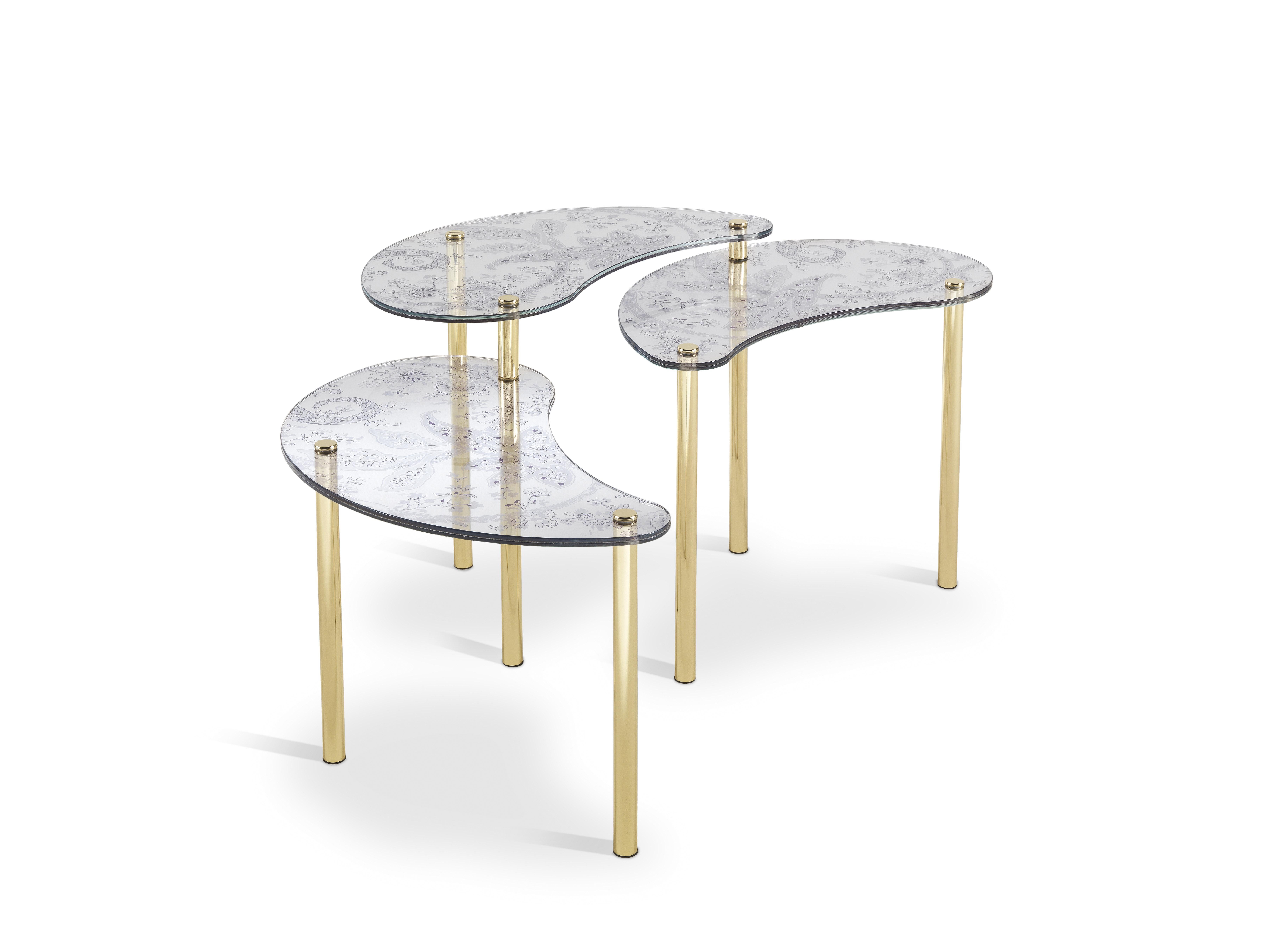 A subtle play of shapes and transparencies, in a small table with a refined composition, consisting of three tops in extra-clear tempered glass, of different heights, each one with a symbolic drop shape. A direct reference to the paisley, the