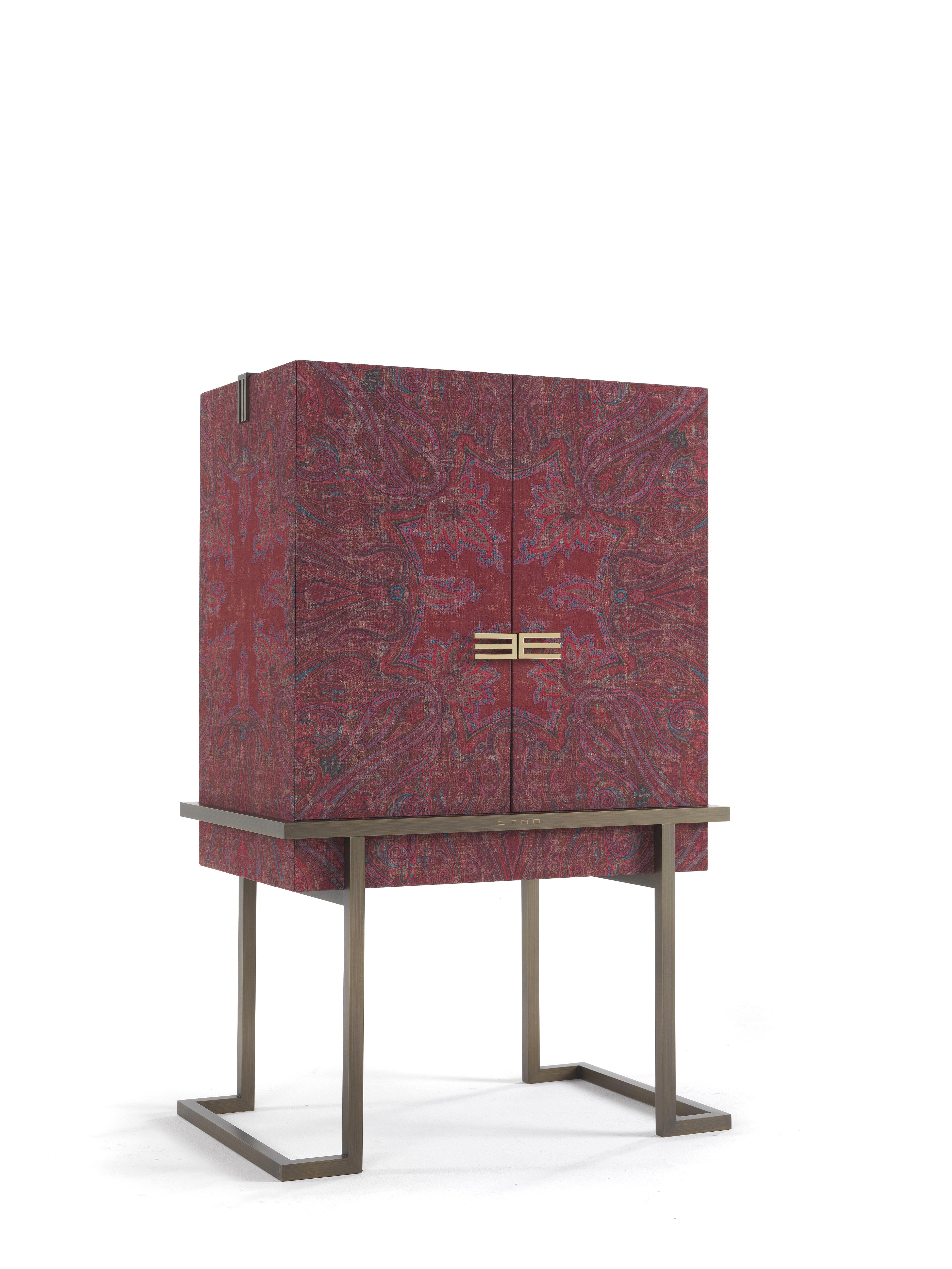 This evocative cabinet recalls the shape of an ancient chest, like those which were sorted in Kolkata, one of the primary commercial centers in India. Embellished by a patinated bronze base, the cabinet is covered with antiqued printed fabric with