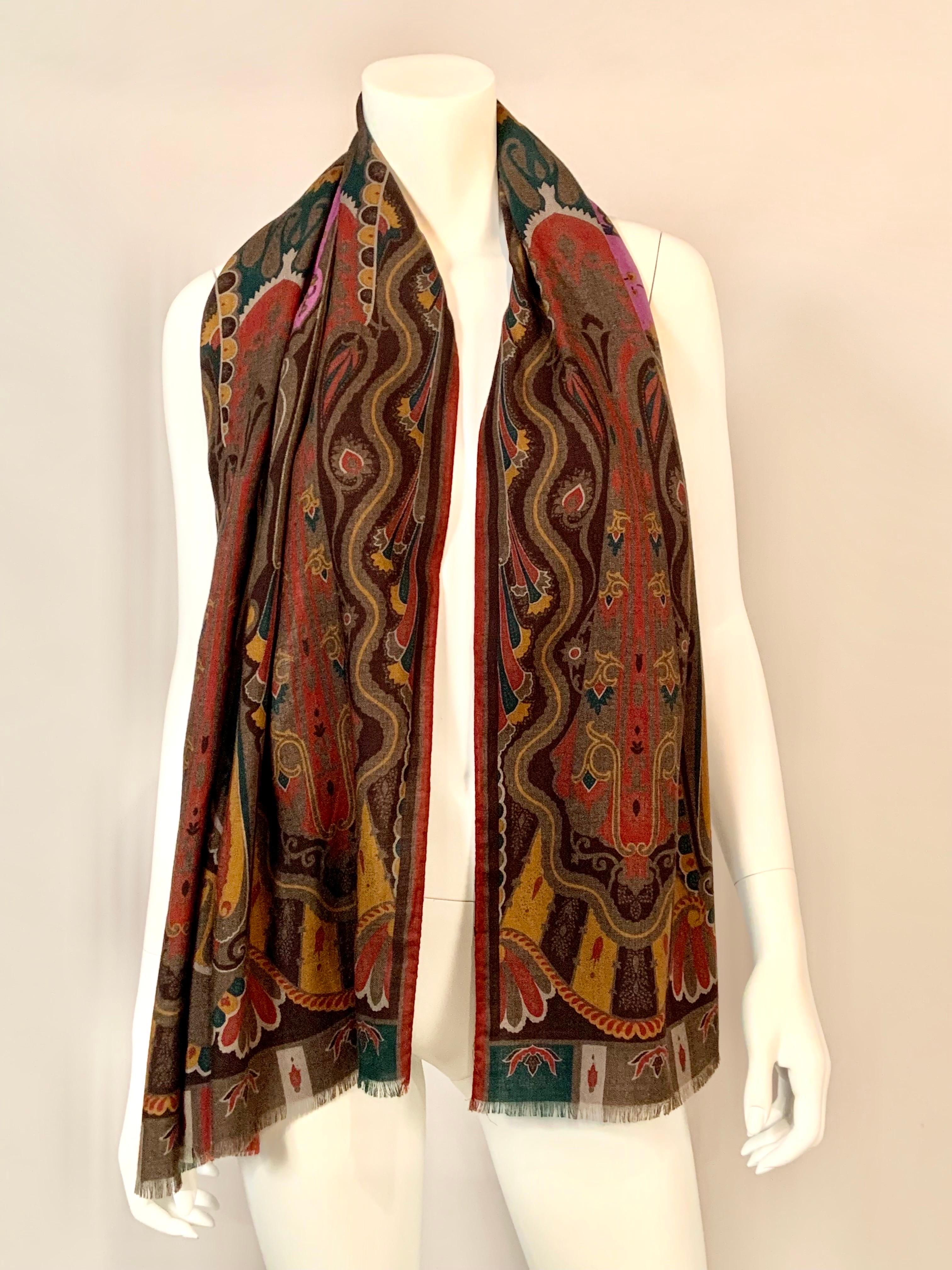 This colorful paisley patterned wool and silk scarf from Etro, Milano has a purple center and paisley designs in shades of olive, dark green, mustard, burnt orange, and brown.It is marked in the design on one corner and also bears the Etro label. It