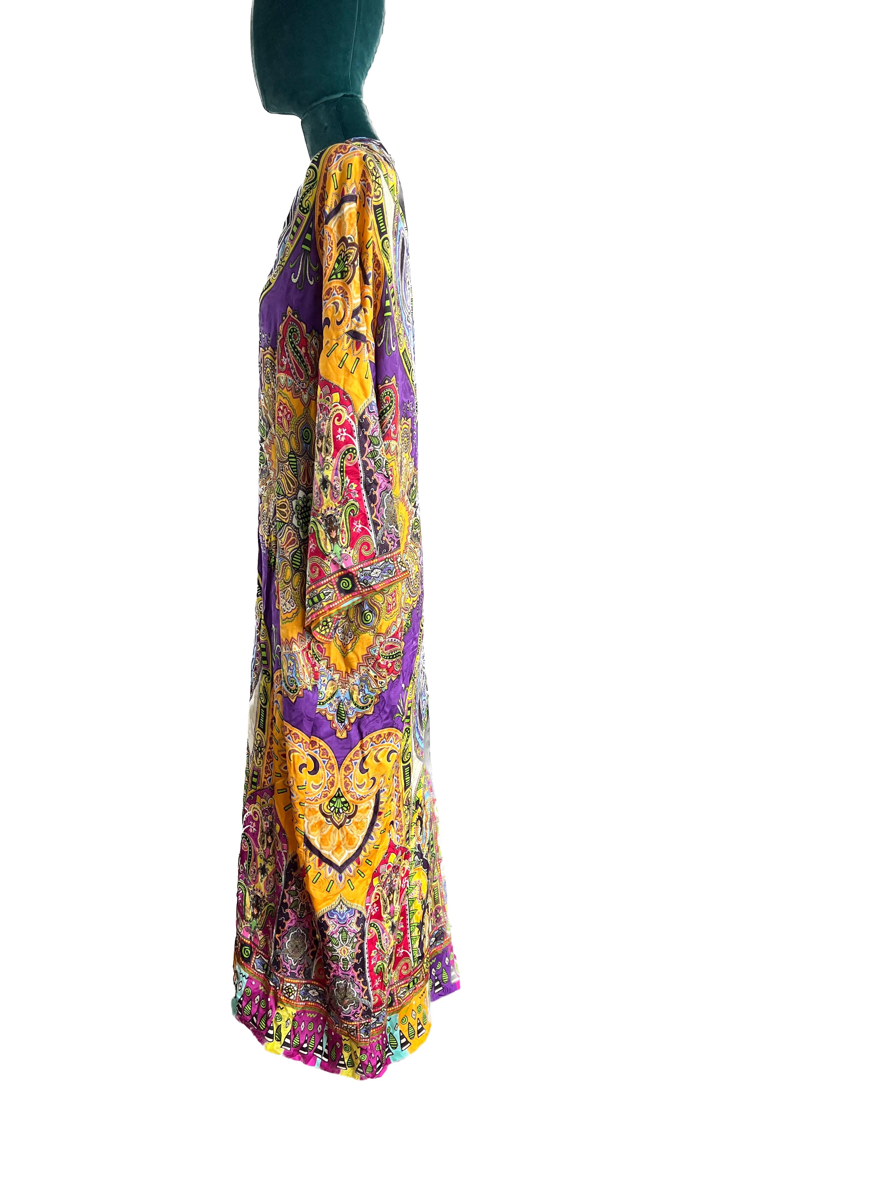 
Behold the captivating Etro kaftan, a wearable masterpiece that transports you to a world of vibrant ethnic elegance. The foundation of this kaftan is a regal purple base, setting the stage for a mesmerizing interplay of colors. Rich splashes of