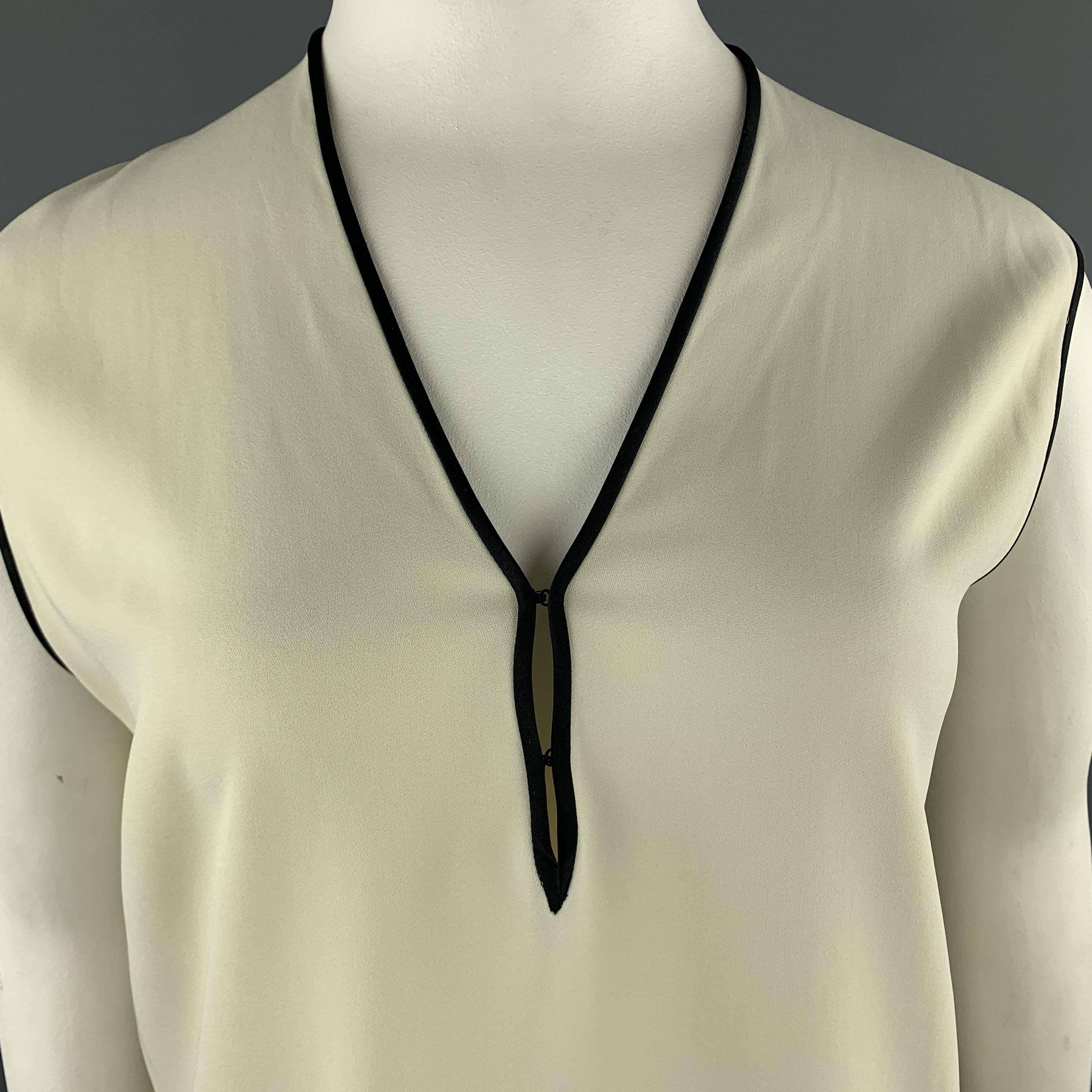 ETRO sleeveless blouse comes in creme crepe with black piping and a V neck hook eye closure neck line. Made in Italy.

Very Good Pre-Owned Condition.
Marked:

Measurements:

Shoulder: 18 in.
Bust: 40 in.
Length: 27 in.