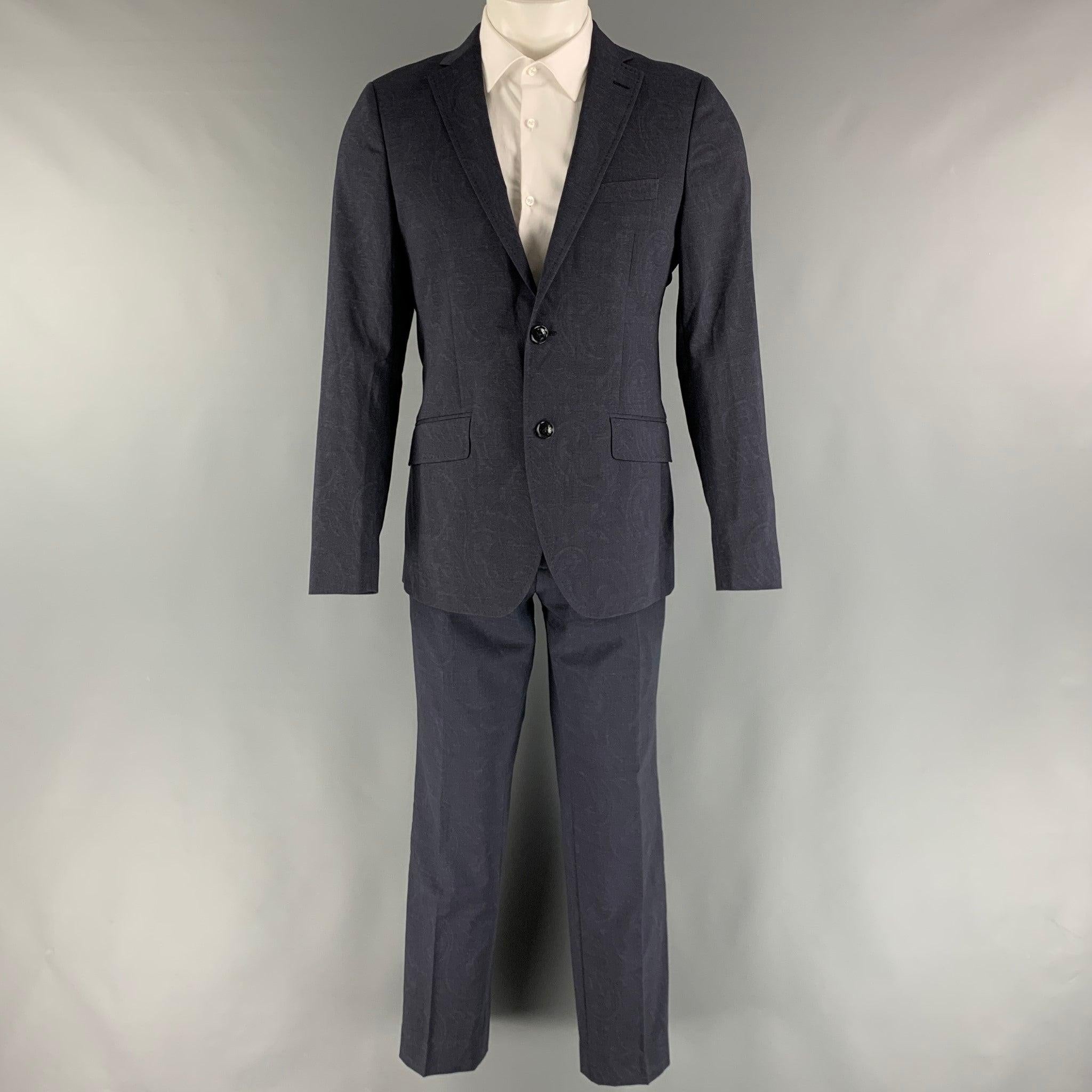 ETRO suit comes in a navy paisley wool and elastane material with a full liner and includes a single breasted, two button sport coat with notch lapel with top stitching and matching flat front trousers. Made in Italy.Excellent Pre-Owned Condition.