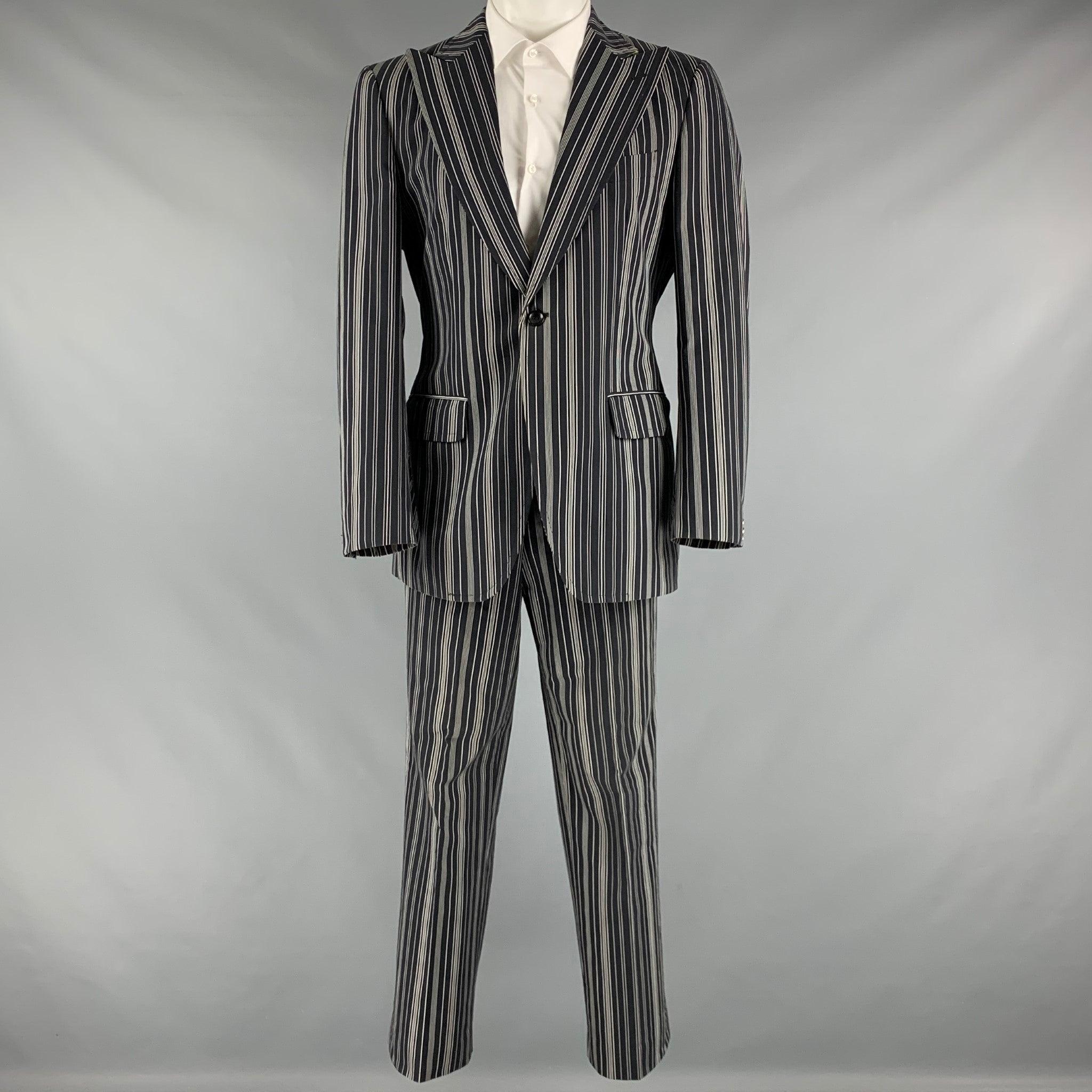 ETRO suit comes in a black and white striped cotton woven material with a full liner and includes a single breasted, single button sport coat with a peak lapel and matching flat front trousers. Excellent Pre-Owned Condition. 

Marked:   50 