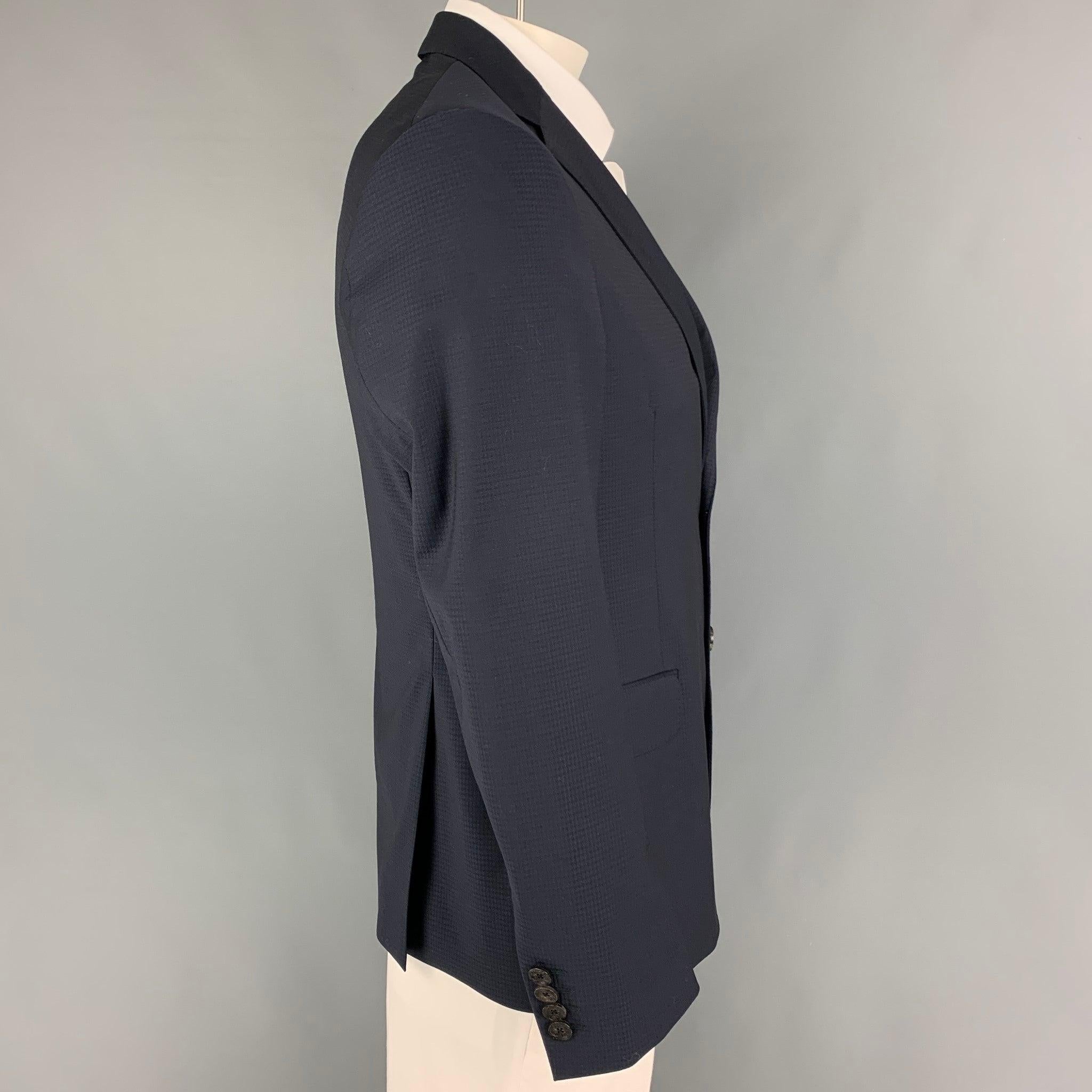 ETRO sport coat comes in a navy checkered wool with a full liner featuring a notch lapel, flap pockets, double back vent, and a double button closure. Made in Italy.Very Good Pre-Owned Condition. 

Marked:   52 

Measurements: 
 
Shoulder: 17.5