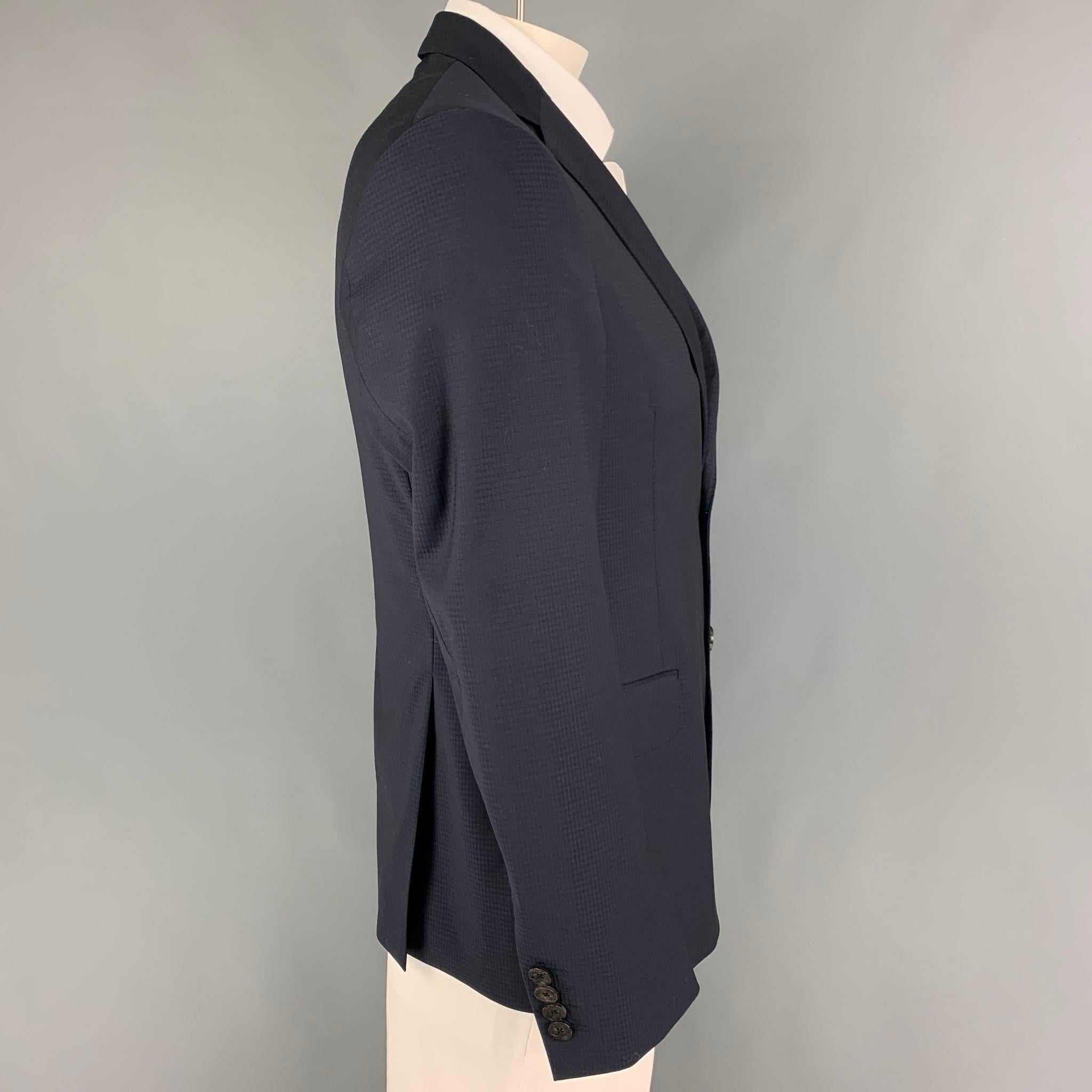 ETRO sport coat comes in a navy checkered wool with a full liner featuring a notch lapel, flap pockets, double back vent, and a double button closure. Made in Italy.

Very Good Pre-Owned Condition.
Marked: 52

Measurements:

Shoulder: 17.5