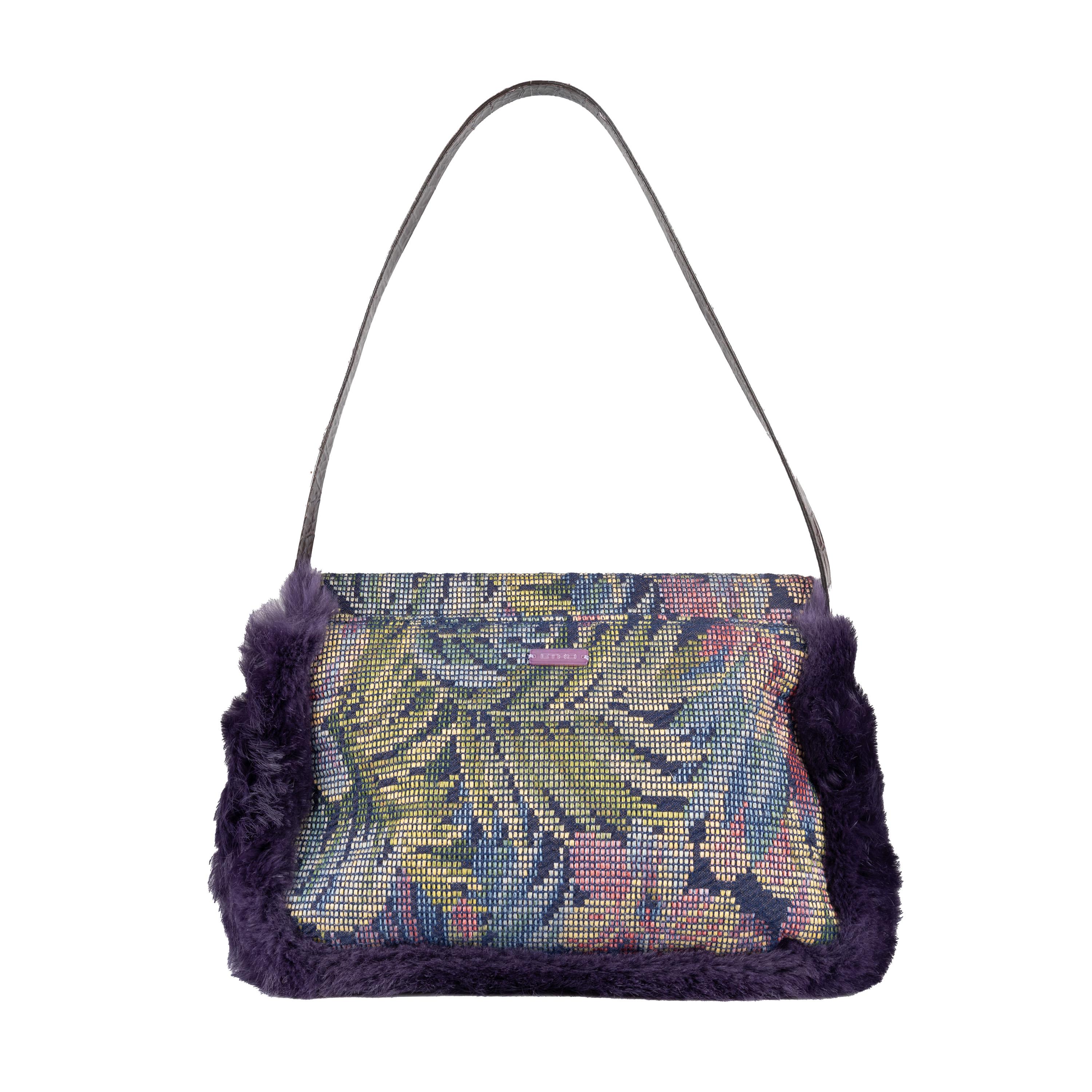 This vintage Etro handbag is crafted from multi color, woven floral print jacquard fabric, adorned with beading, sequins and plush purple fur. It has a flap with snap closure and a sturdy embossed leather strap. The interior is lined with luxurious