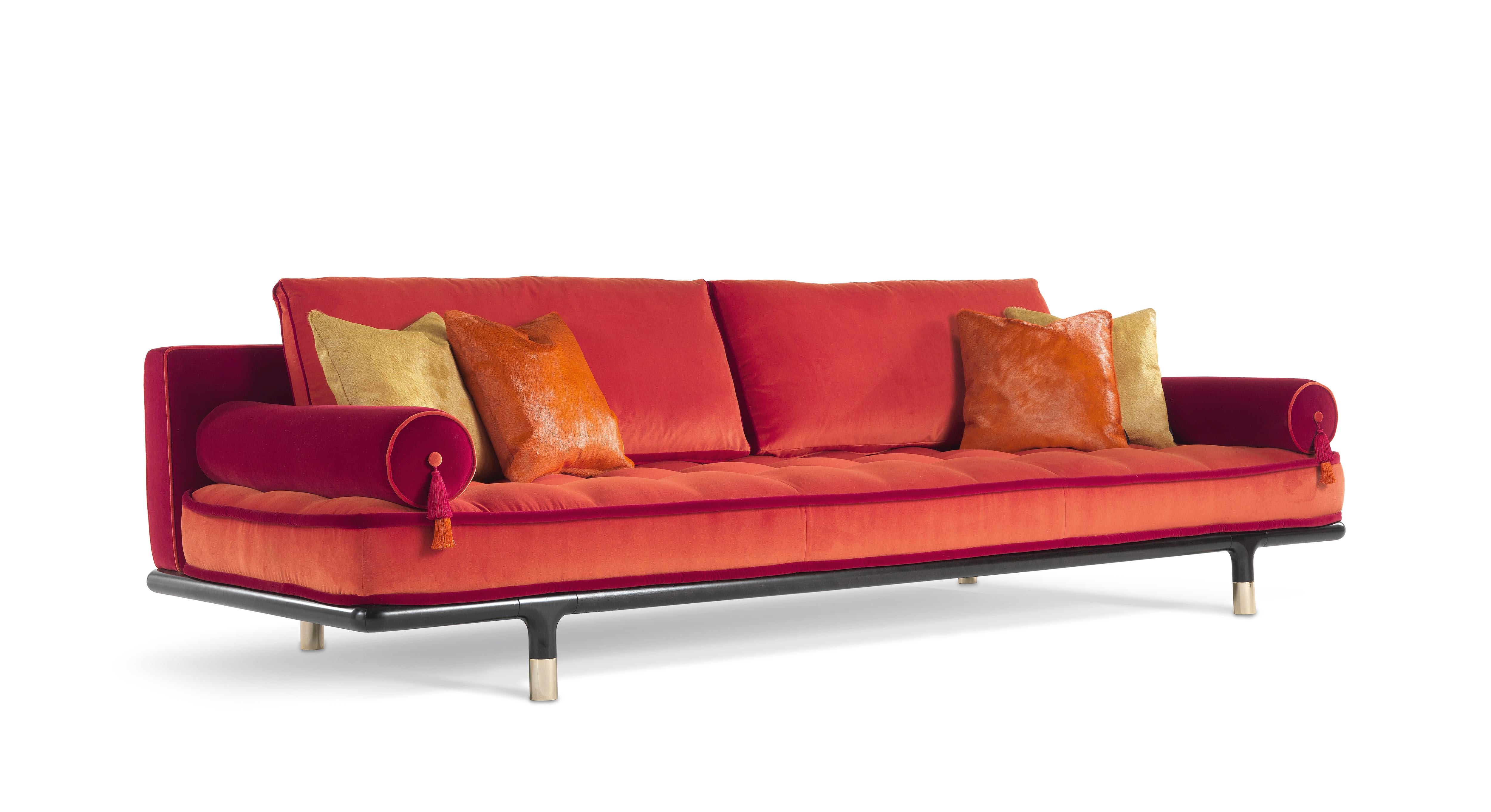 Ein Sofa mit einem einladenden und komfortablen Aussehen, das durch die Matratzenform des Sitzes unterstrichen wird. Raffinierte Details wie die polierten Messingspitzen des Sockels und die Rollenkissen mit dekorativen Quasten verstärken den