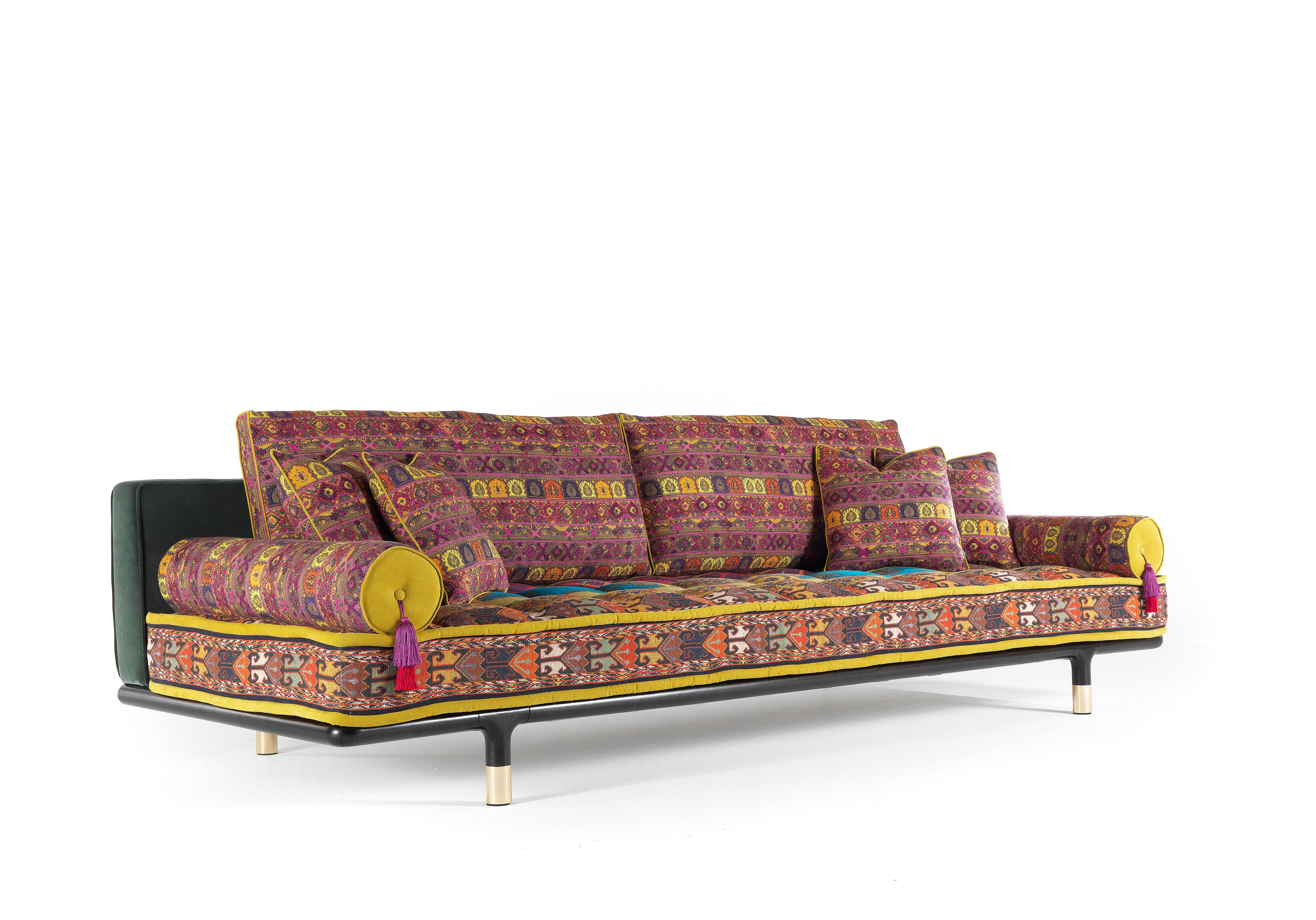 A sofa with a welcoming and comfortable look, emphasized by the mattress conformation of the seat. Refined details such as the polished brass tips of the basement and the roll cushions with decorative tassels enhance the whole effect, showing the