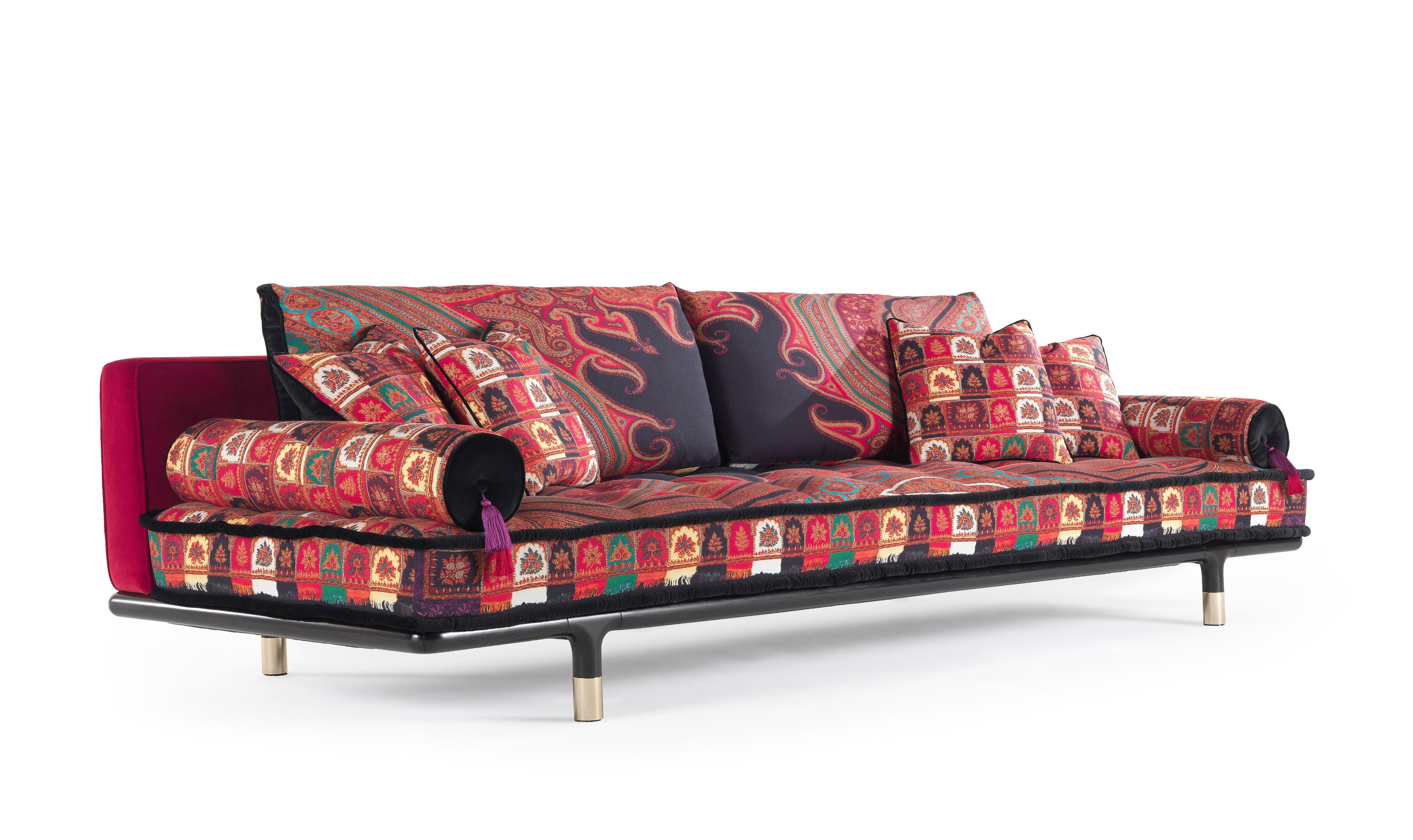 A sofa with a welcoming and comfortable look, emphasized by the mattress conformation of the seat. Refined details such as the polished brass tips of the basement and the roll cushions with decorative tassels enhance the whole effect, showing the
