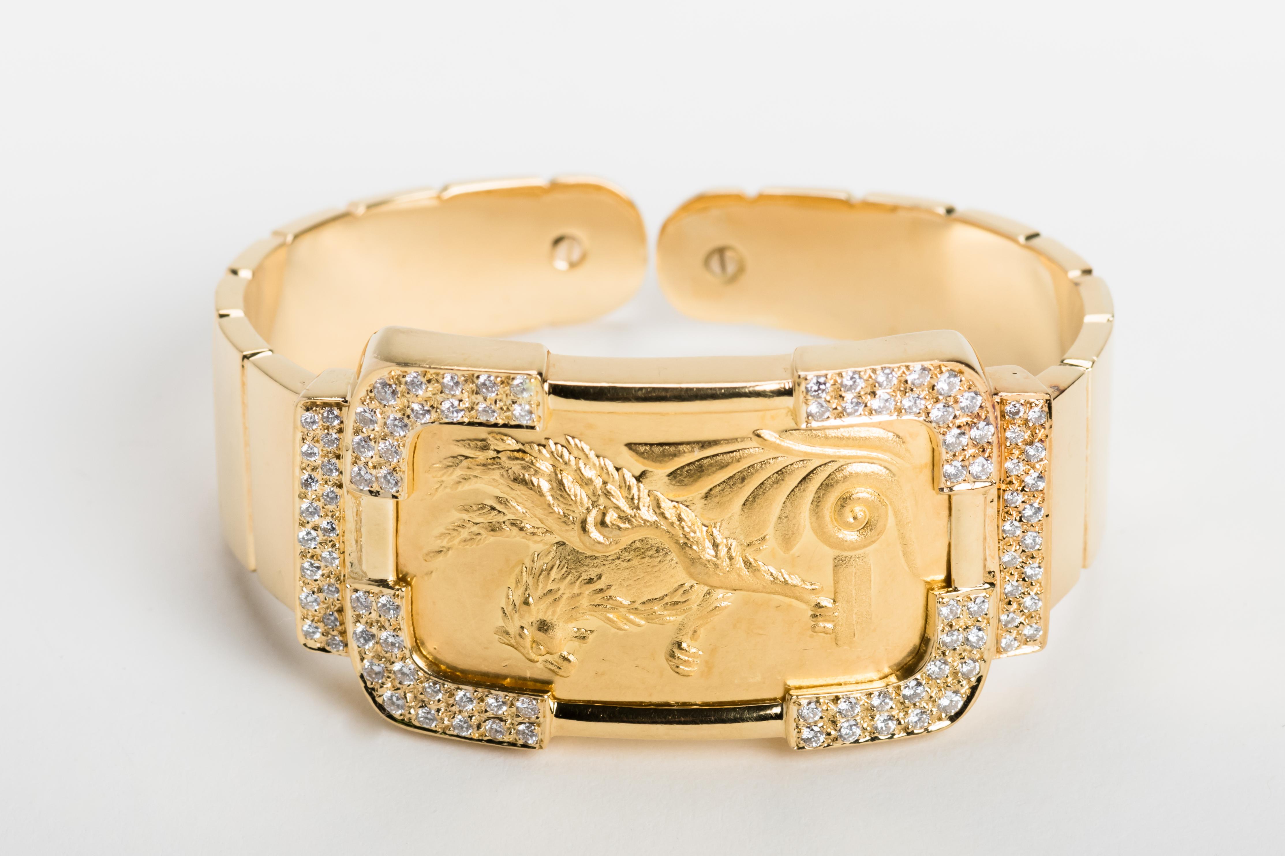 This beautifully custom made yellow gold flexible cuff bracelet has a 24 karat gold winged lion in the center surrounded by diamonds and a 18 karat gold band. It is signed by Etros and Takis. The bracelet is flexible and can fit any size