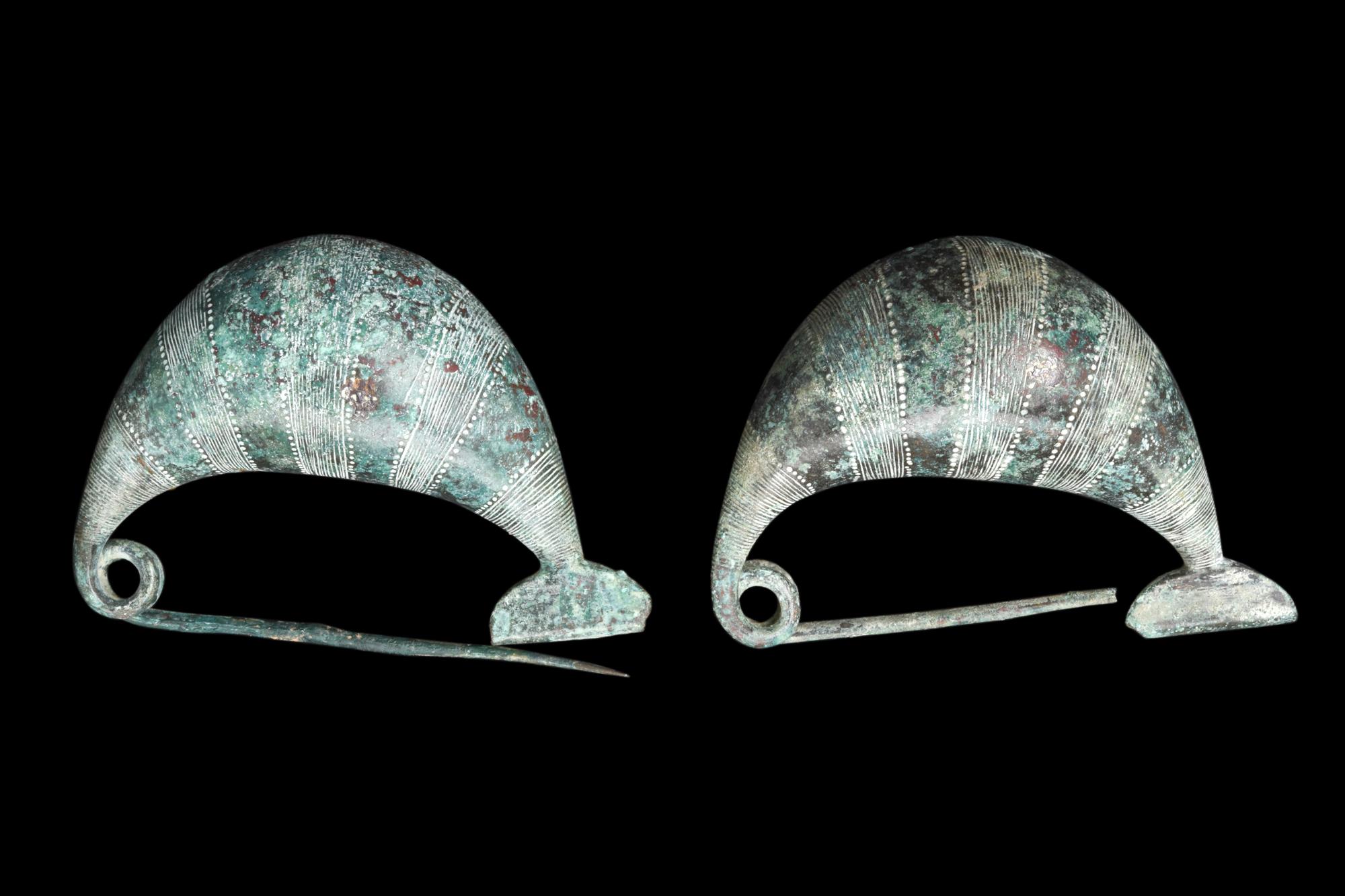 Ein Paar etruskische Bronzefibeln vom Typ Sanguisuga. Jede Brosche besteht aus einem dicken Bogen, einem langen Verschluss, einer zweigängigen Feder und einer geraden Nadel. Die Sanguisuga-Fibeln tragen quer verlaufende Bänder mit geriffelten und