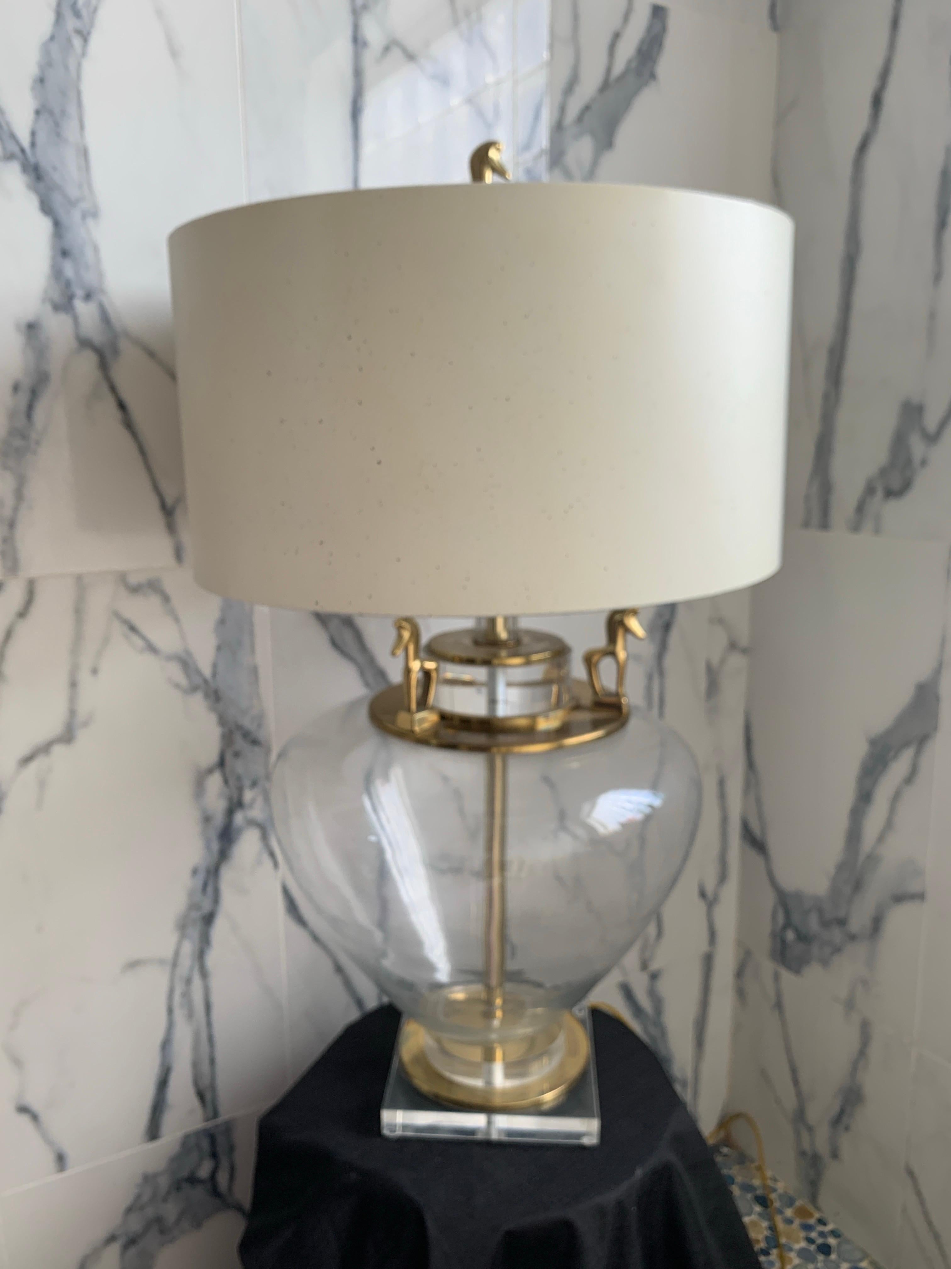 A very special and unique lamp. Large, clear glass table lamp with brass Etruscan horses on the top of lamp Finial to the set of four around the upper part of the glass base. In the iconic style of Fredrick Weinberg. Square lucite base. It came from