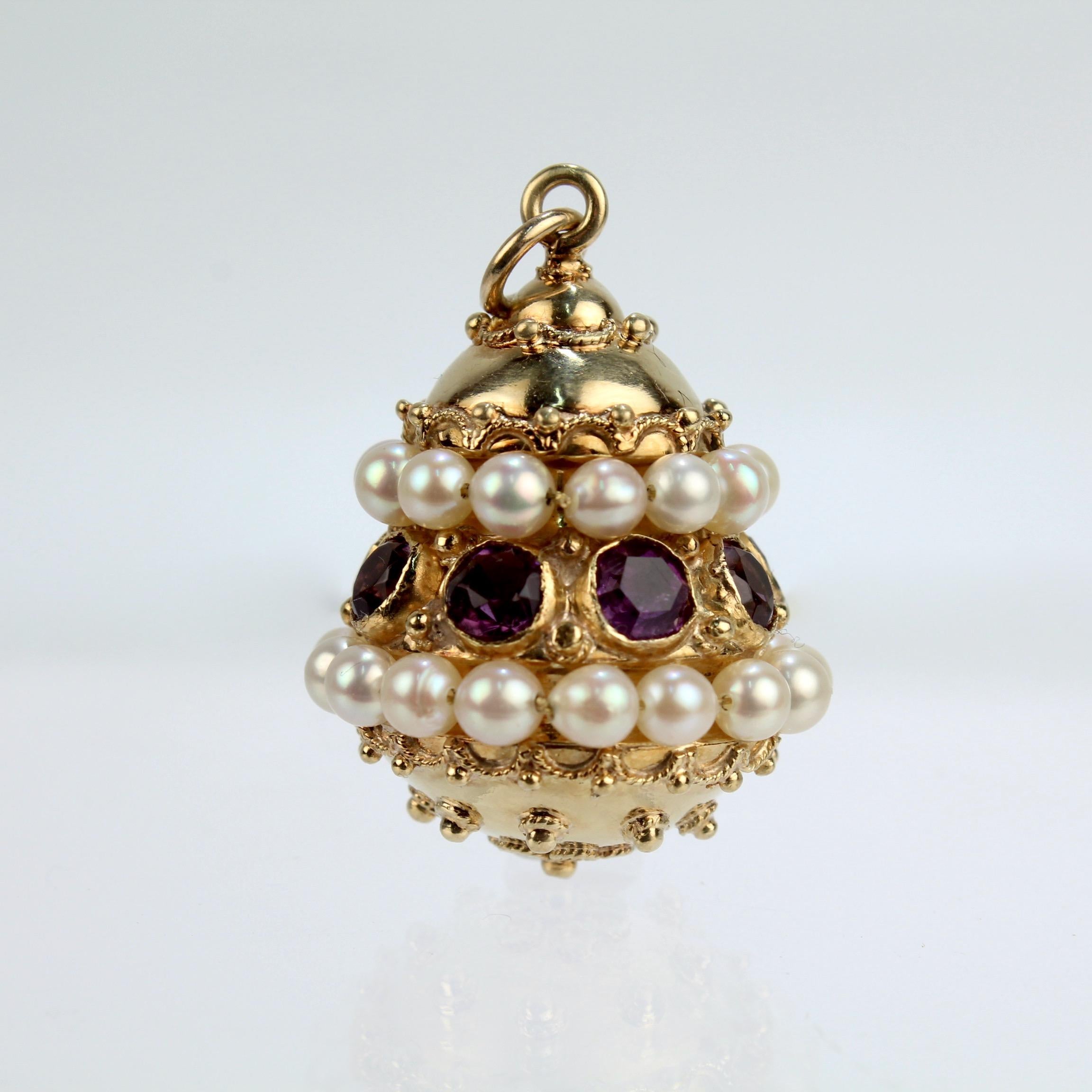 A very fine vintage gold, amethyst and pearl Etruscan Revival style pendant or charm. 

The bell shaped 18k gold pendant is ornately set with wire work and granulation throughout. At its center is a row of bezel set round amethyst gemstones that run
