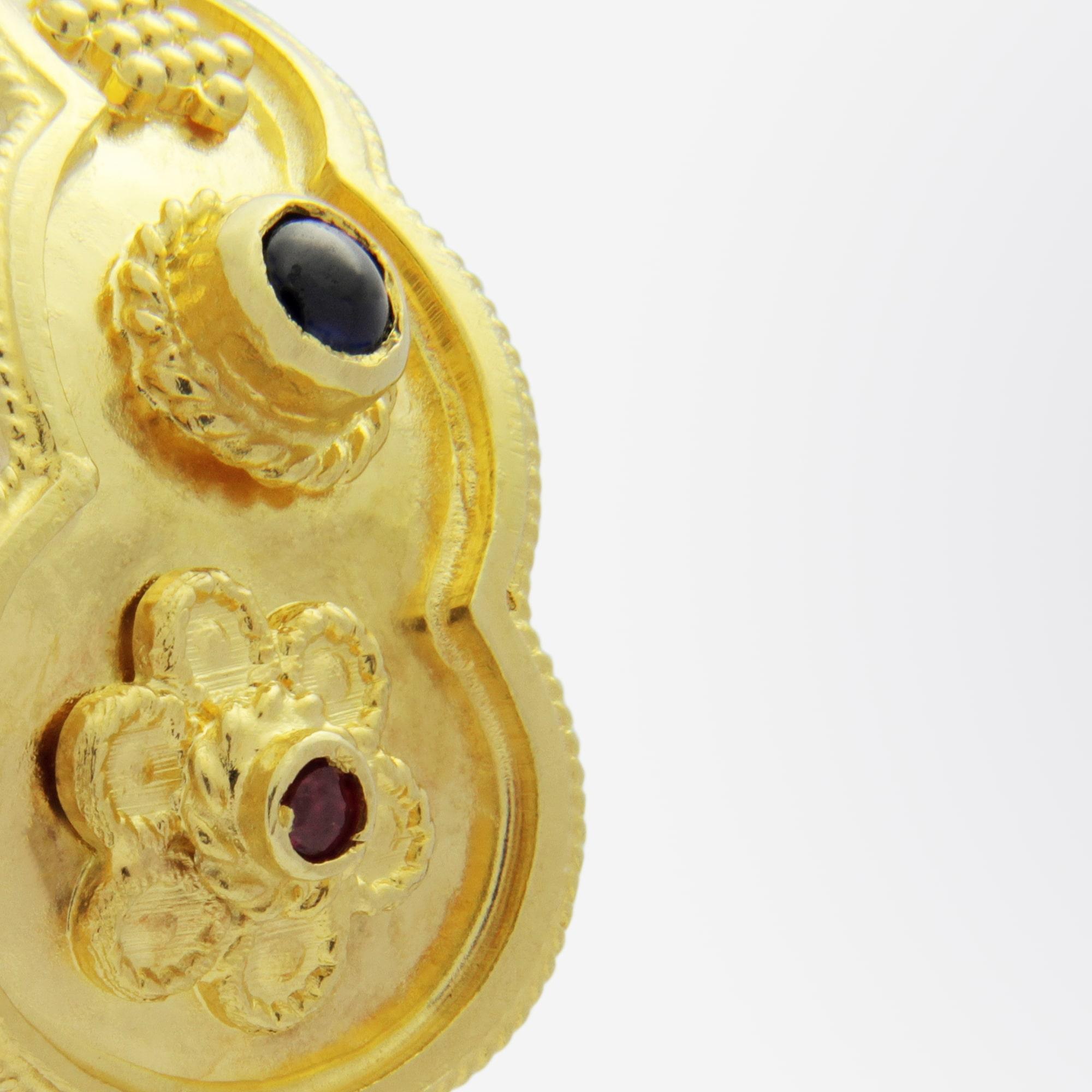 A lovely pair of 18 karat yellow gold, sapphire and ruby ear clips in the Etruscan Revival taste. The curved and scalloped 'tear drop' shaped profile hugs the ear and each clip features a single round cut ruby and a single cabochon cut sapphire