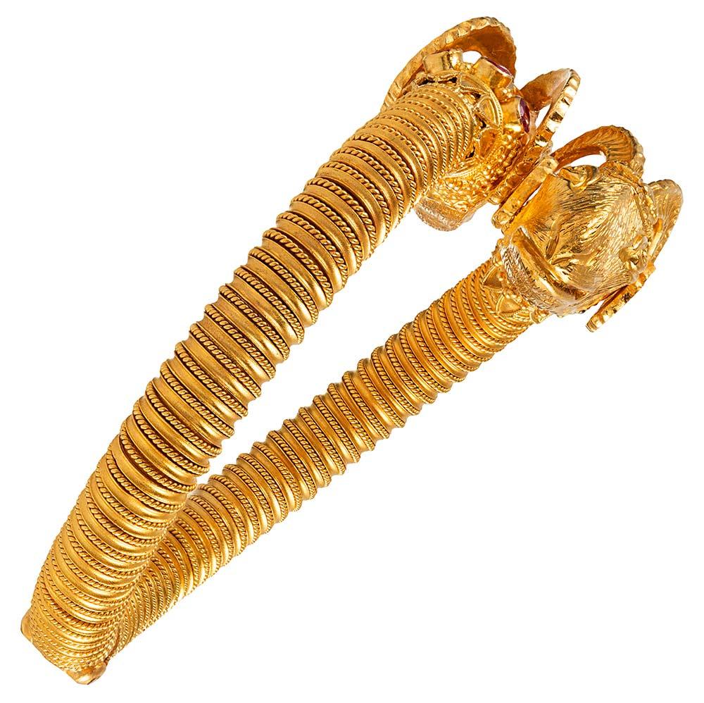 A contemporary rendering of Etruscan design, this 18 karat yellow gold bracelet is fashioned with extraordinary detail and abundant style. The lifelike creatures gaze past each other, their collars decorated with bezel set rubies (1.10 carats in