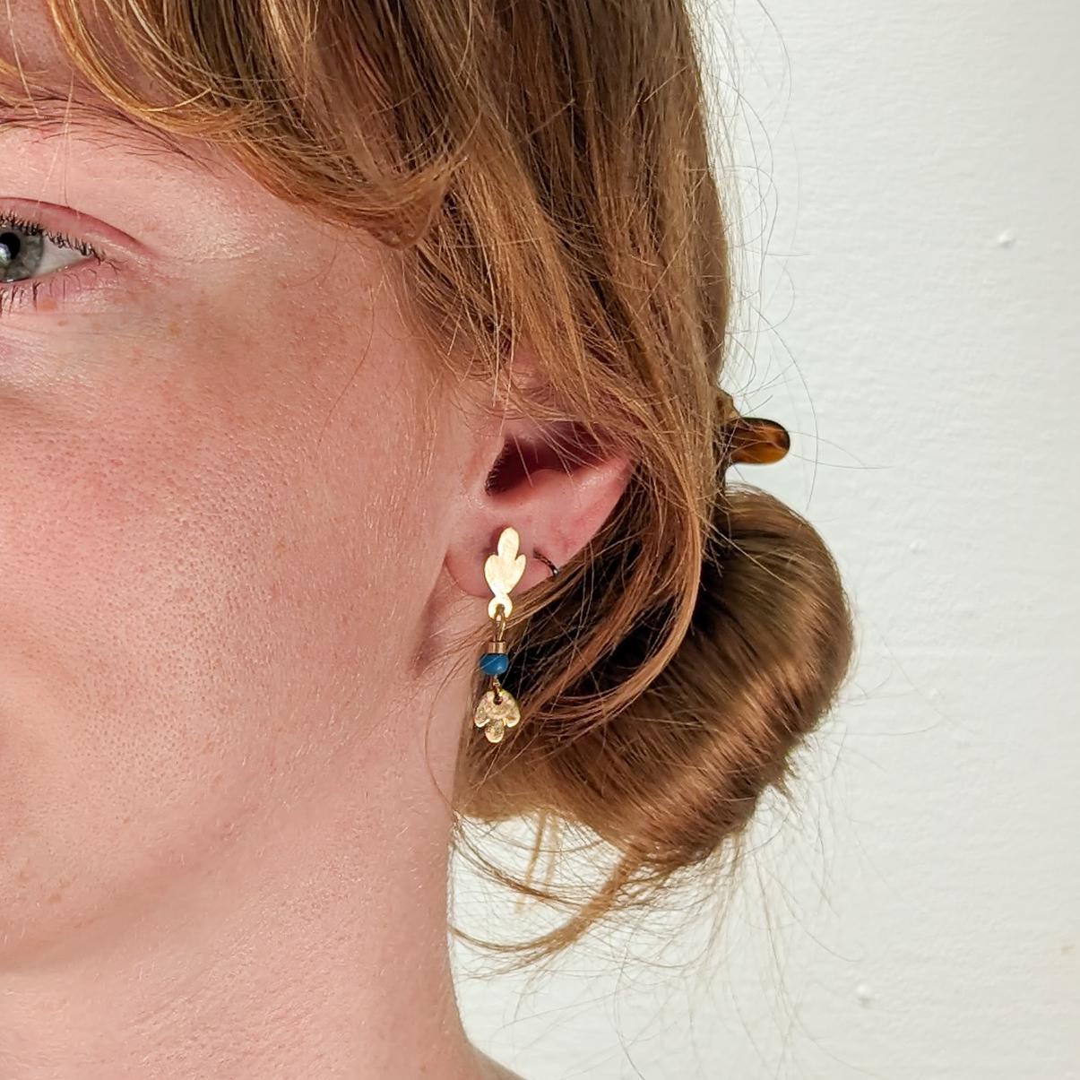 A fine pair of Etruscan Revival style earrings.

By the New York City Modernist female goldsmith Resia Schor. 

In 14k gold.

Comprised of hand-built 14k gold loop elements supporting drops with blue glass beads and leaf terminals. 

Designed with