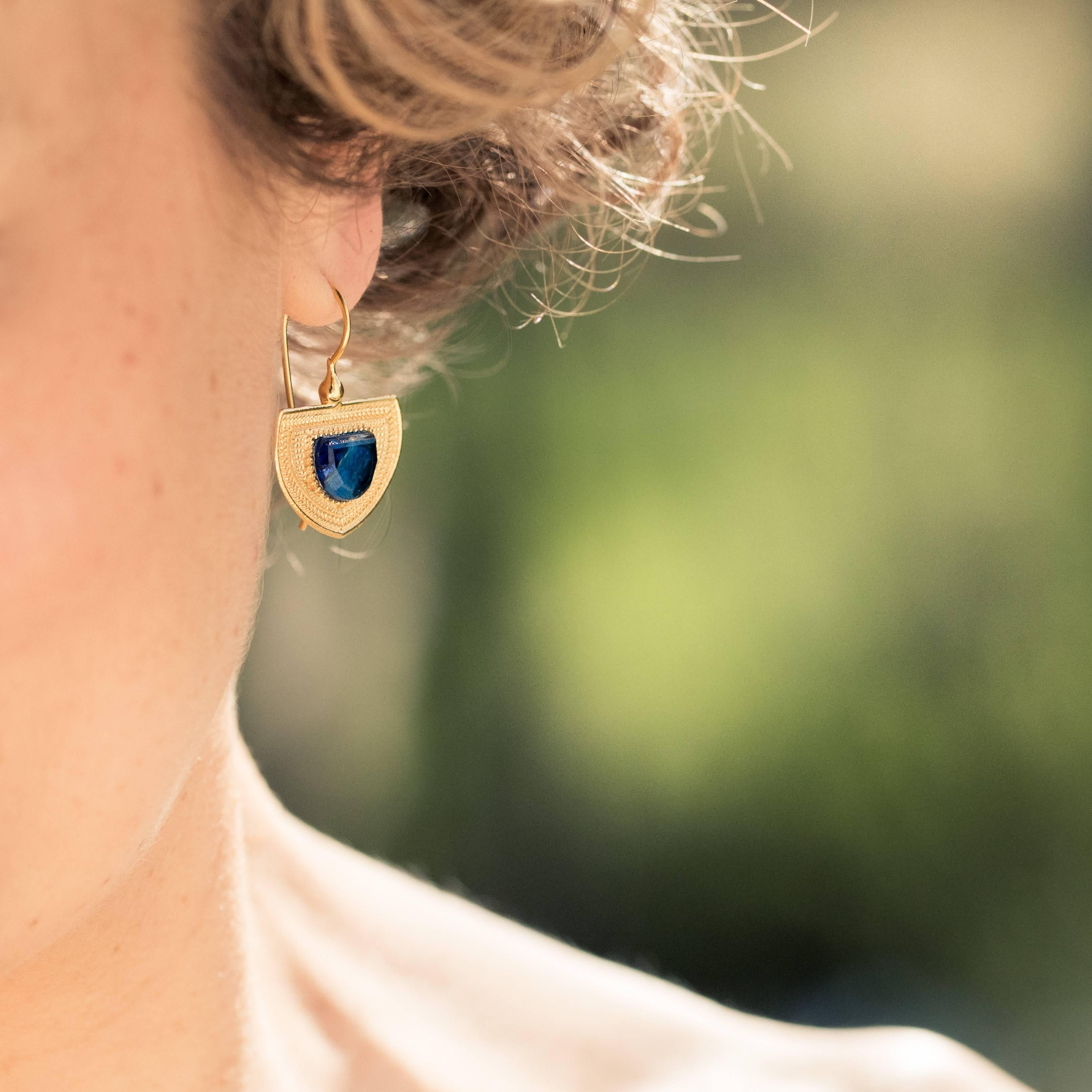 For pierced ears.
Pair of earrings in silver and yellow gold.
Sleepers shaped, they are formed of a chiseled motif set in the center of a blue cut stone. The clasp system is a gooseneck with safety hook.
Length: 3.2 cm, width: 2.2 cm.
New jewel