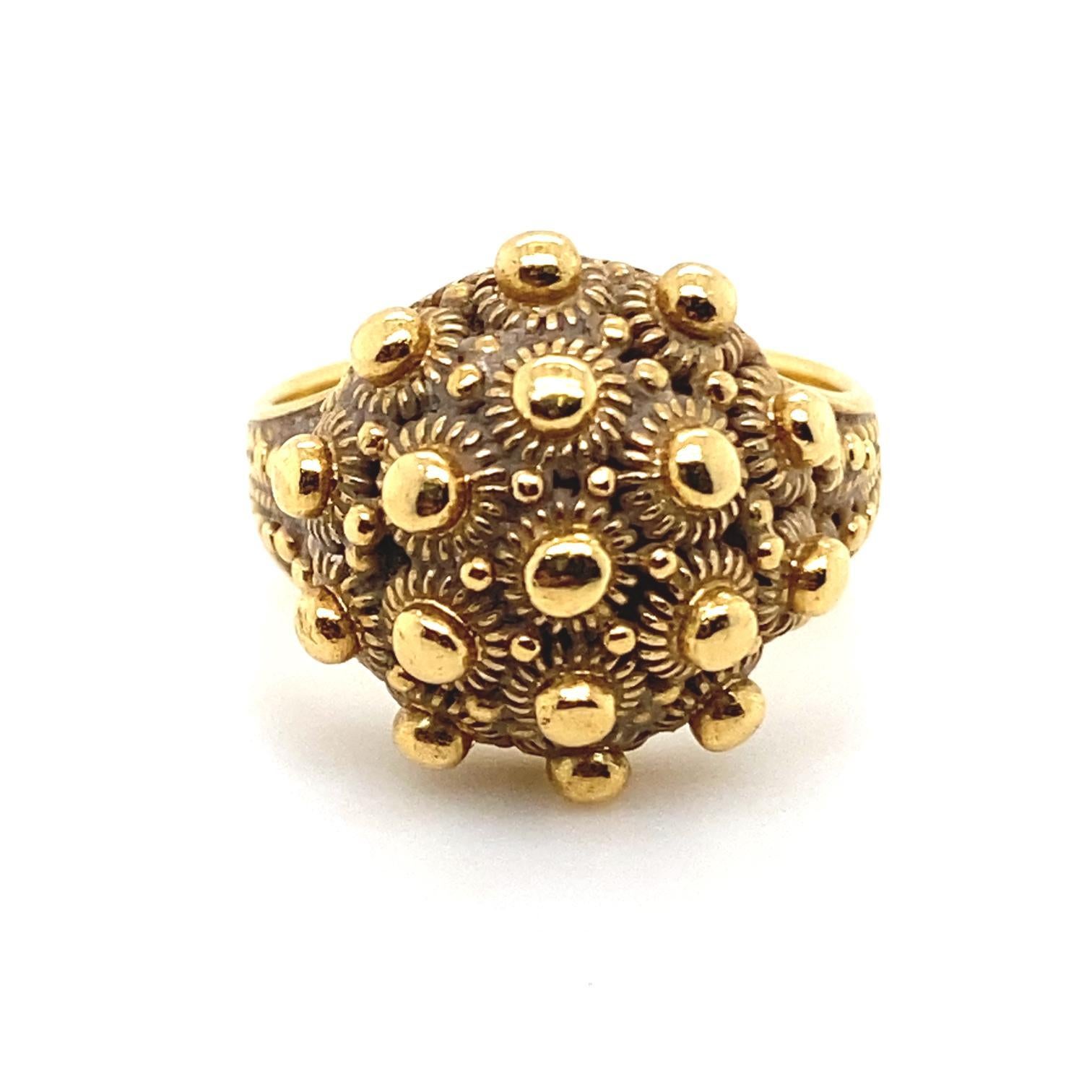 An Etruscan style 18 karat yellow gold ring

This ring features a domed circular base studded with tiny polished gold balls, leading to a tapered band, also with engraved relief detail.

The strong Etruscan Style of this ring is inspired by 19th