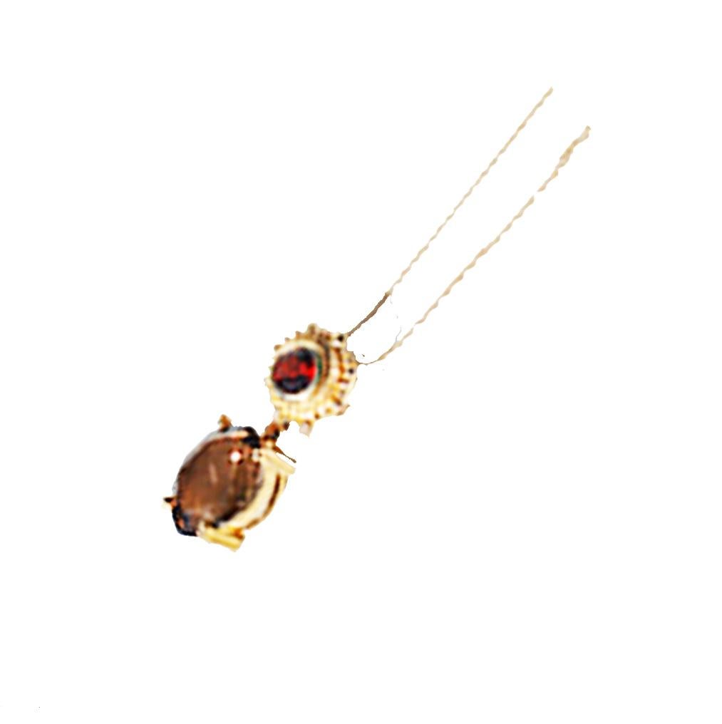 Etruscan Style Pendant featuring a Topaz oval shaped and is dropped from a starburst yellow gold disk featuring a garnet. 
The cognac colored, oval shaped smokey topaz measures 10 x 12 mm and dangles from the yellow gold disk holding garnet.
Garnet