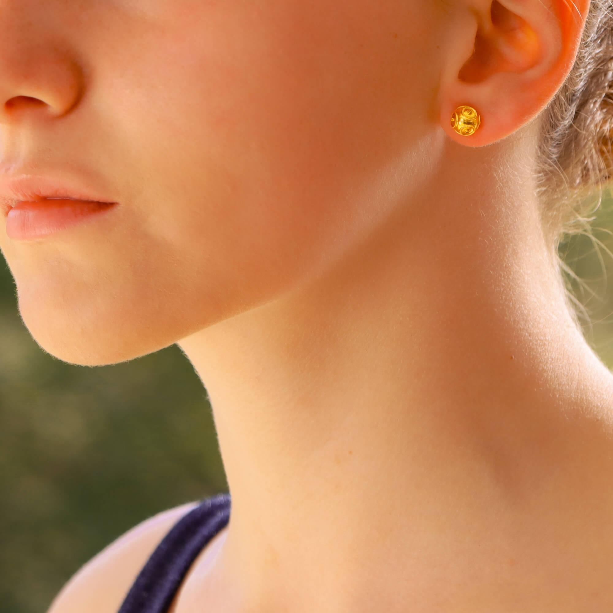 A pair of Etruscan-style orb stud earrings in 18-karat yellow gold. 
Each earring is composed of a round orb decorated with open tubular motifs surrounded by ropework detailing, they are secured to the reverse with a post and butterfly fitting.