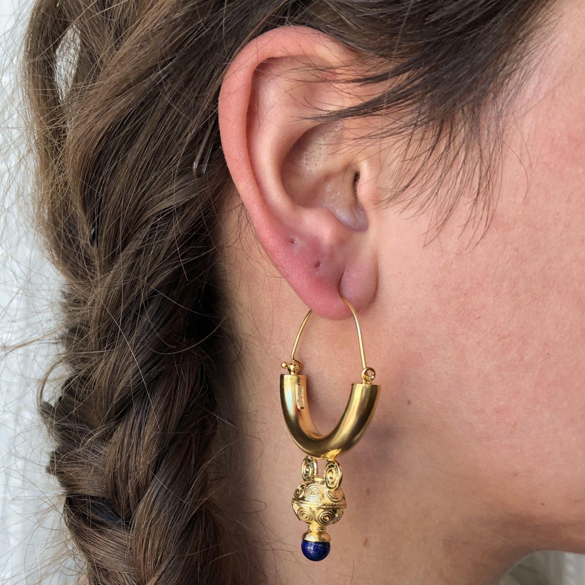 For pierced ears.
Pair of earrings in silver, yellow gold and vermeil.
Important creoles that are threaded through the back of the ear, they support each one a chiseled pattern of Etruscan motifs that ends with a blue glass pearl.
Height : 5.9 cm,