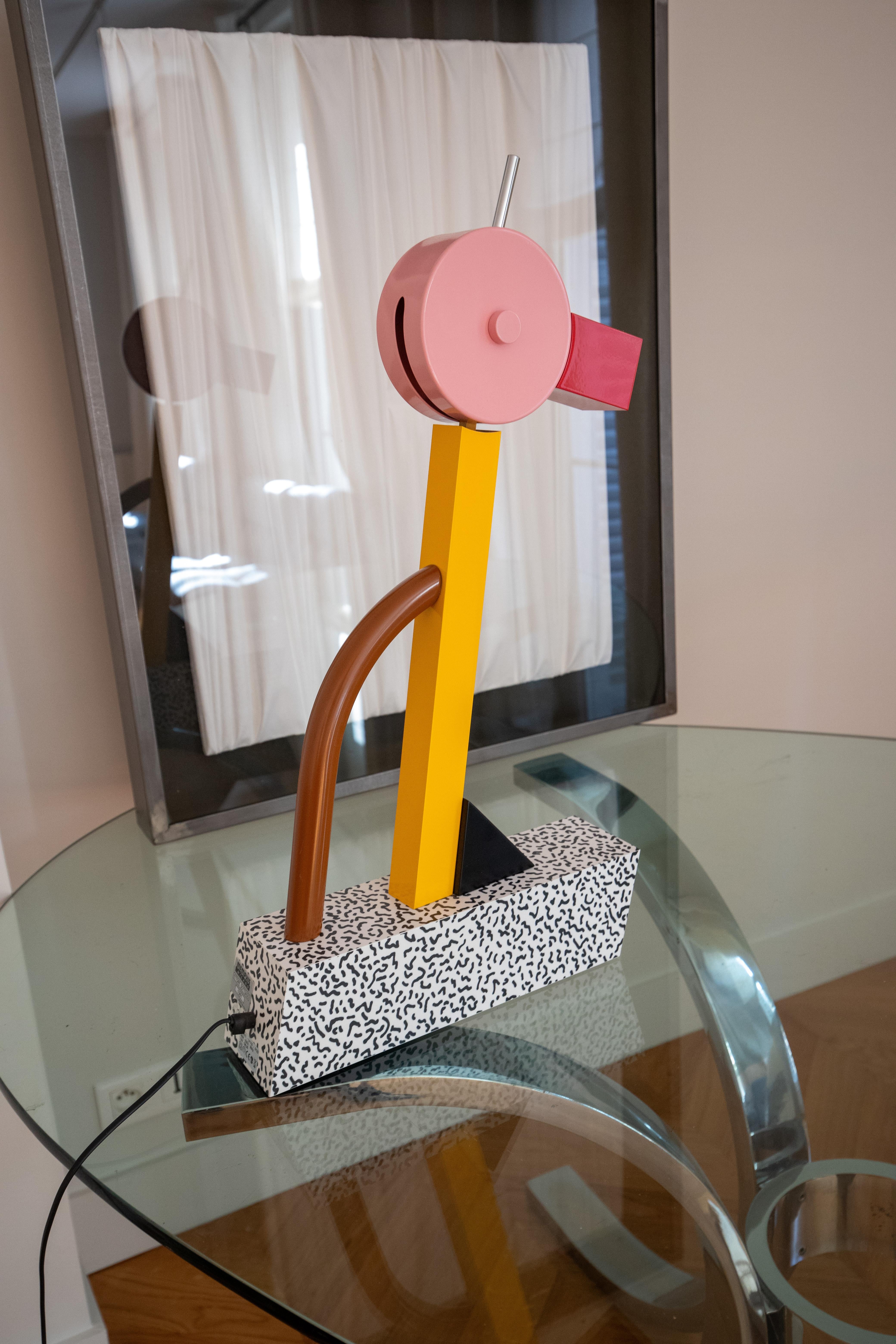 Tahiti designed by Ettore Sottsass for Memphis Milano is a table lamp made with a rotating head in polychrome enamelled metal on a plastic laminate base with black and white Bacterio pattern.