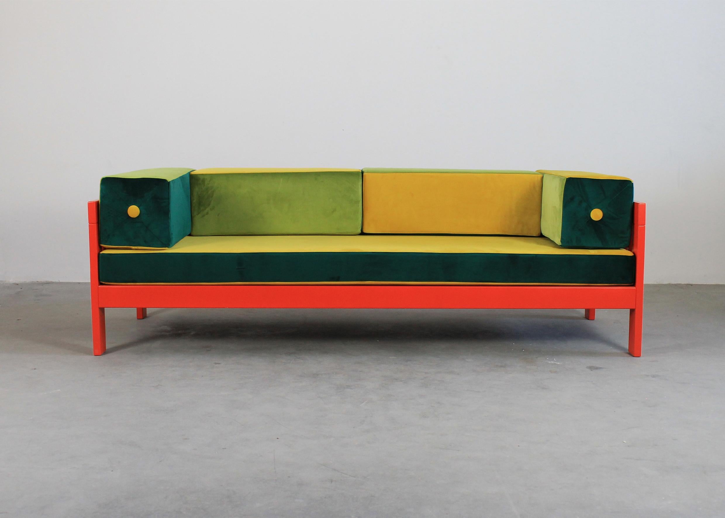 Two-seater Califfo sofa with a structure in a orange/red lacquered wood seat and back are structured by cushions upholstered with velvet fabric in a mixed shades of yellow and greens which perfectly contrast with the bright color of the sofa frame.