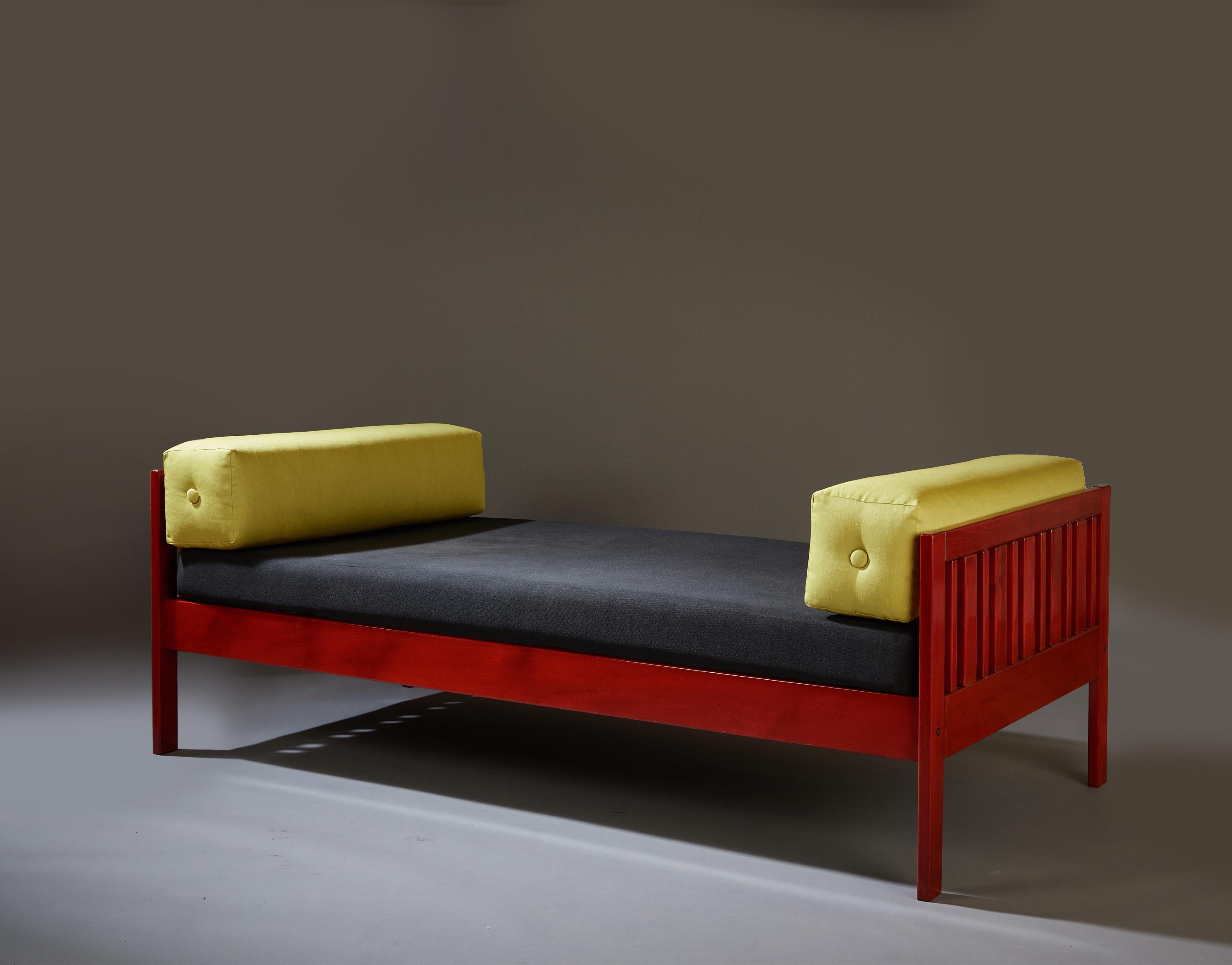 Ettore Sottsass (1917-2007) 

A lively and playful modernist daybed or sofa by Memphis Milano founder Ettore Sottsass, in red lacquered walnut with a black-upholstered cushion and two bolster pillows in chartreuse. 

An early work by the