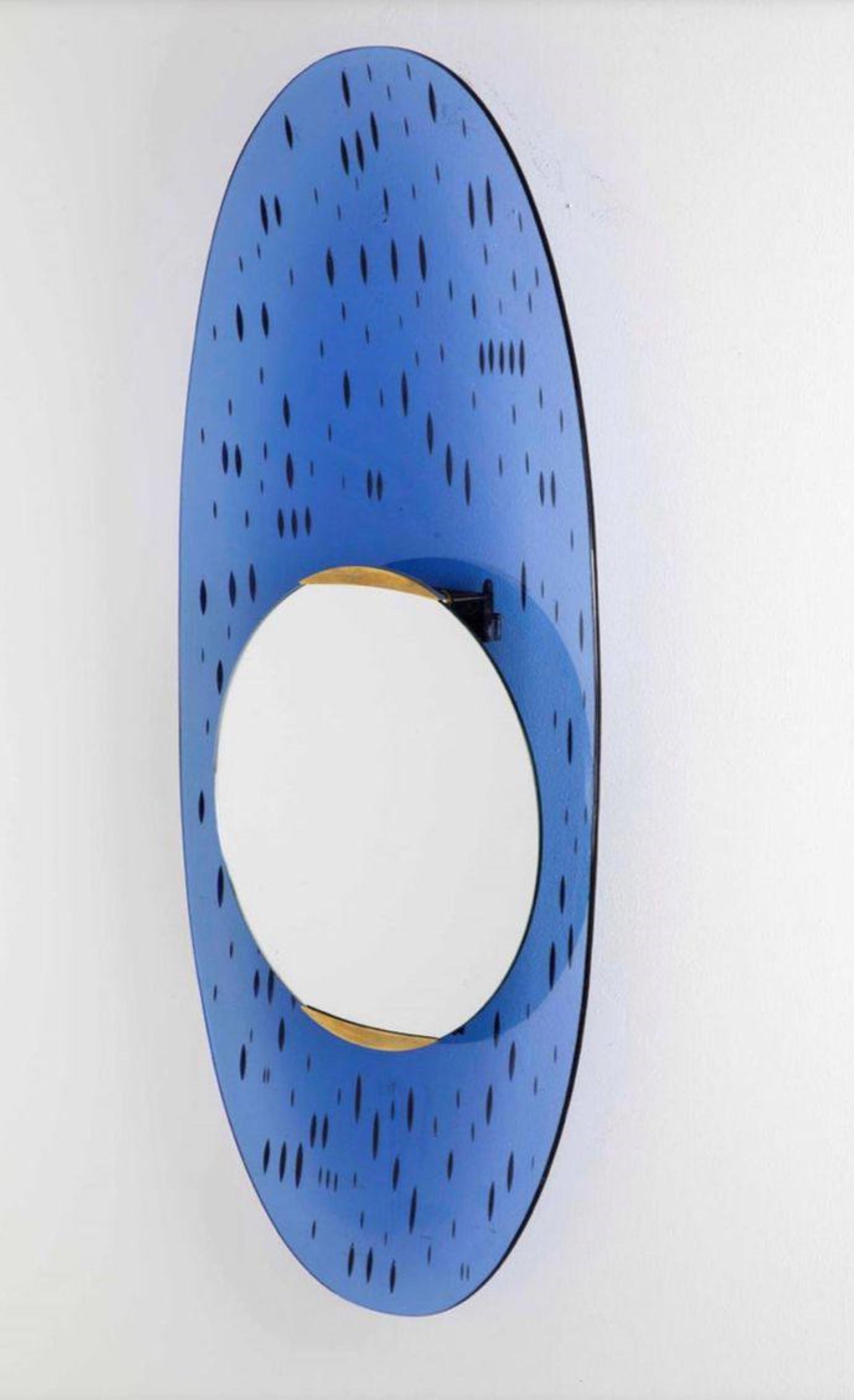 Santambrogio & De Berti
Specchio curvo ovale
Vetro colorato blu, ottone e vetro specchiato.
Vetro blu curvato con incisioni argentate nel retro che assimilano e somigliano a  tante gocce nella parte esteriore del vetro.
Espiga central circular
