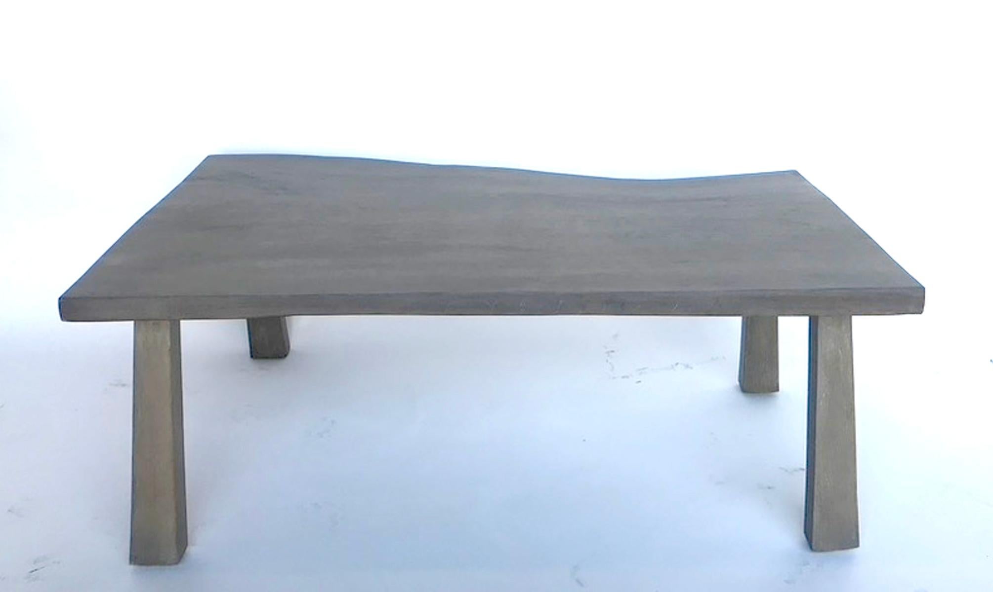 Live edge eucalyptus wood coffee table with straight legs. Medium soft gray finish. Smooth surface. The depth of the table varies from 22.5 inches to 29.5 inches.