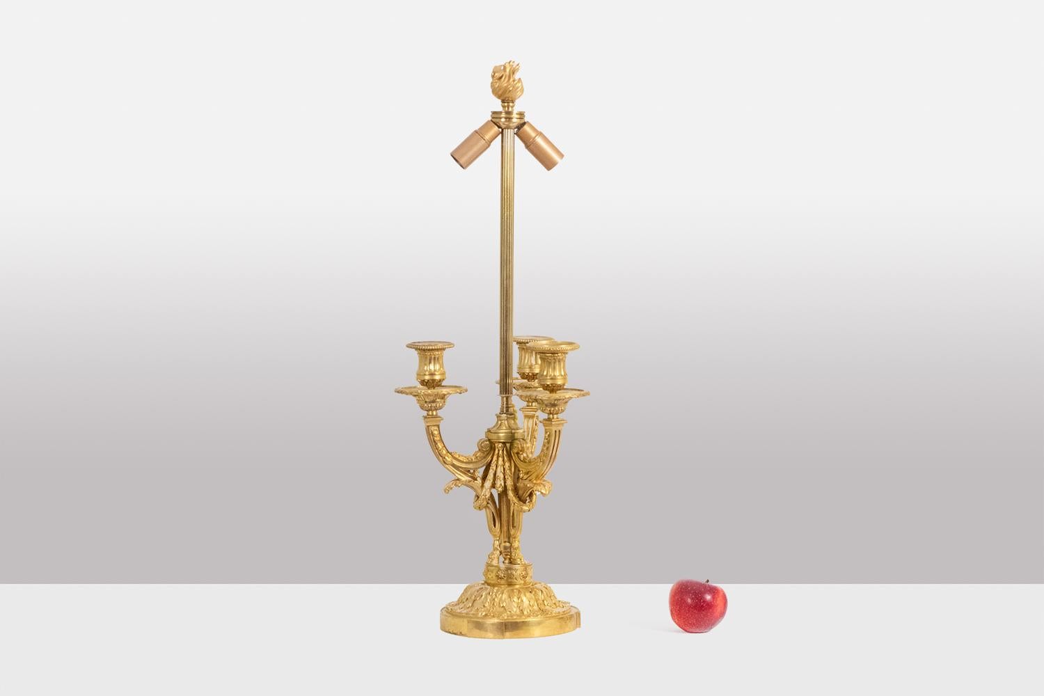Eugène Bazart Paris, signé.

Candélabre en bronze doré, monté en lampe, avec base circulaire, bras décorés de guirlandes et se terminant au sommet par une flamme stylisée.

Travail français, période Napoléon III, vers 1880.

Système électrique neuf