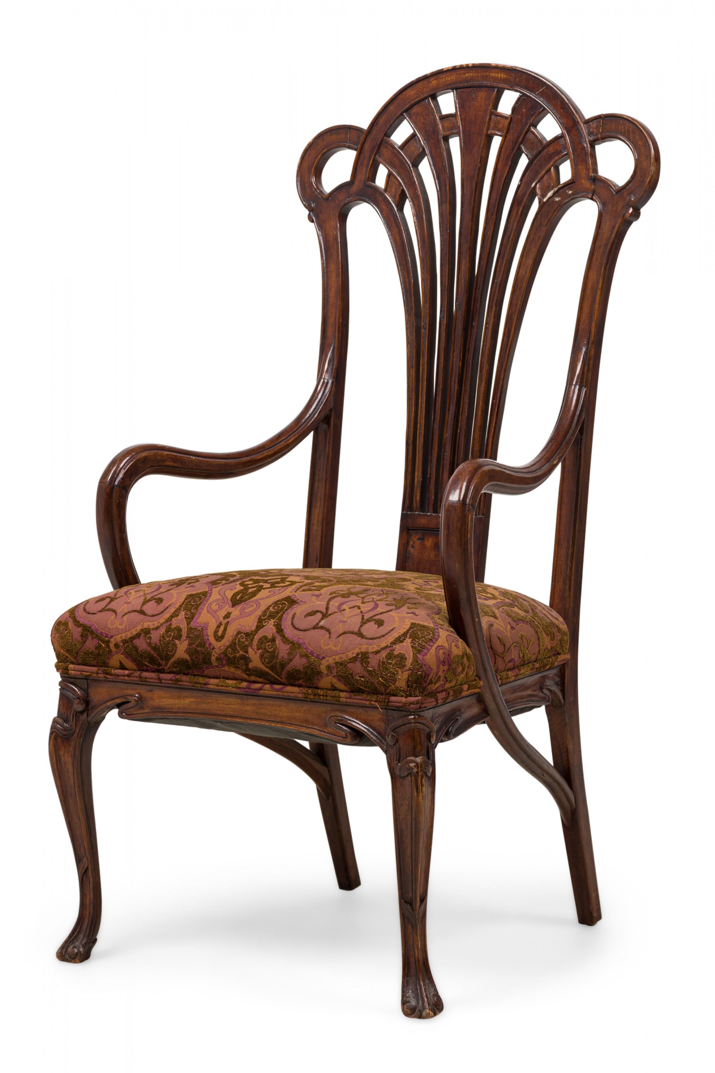 Art Nouveau French mahogany armchair with a pierced fan form connected to curved sculptural arms, the seat upholstered in a textured earth tone and mauve scroll & foliate patterned fabric, with a fluidly carved decorative frieze and front cabriole