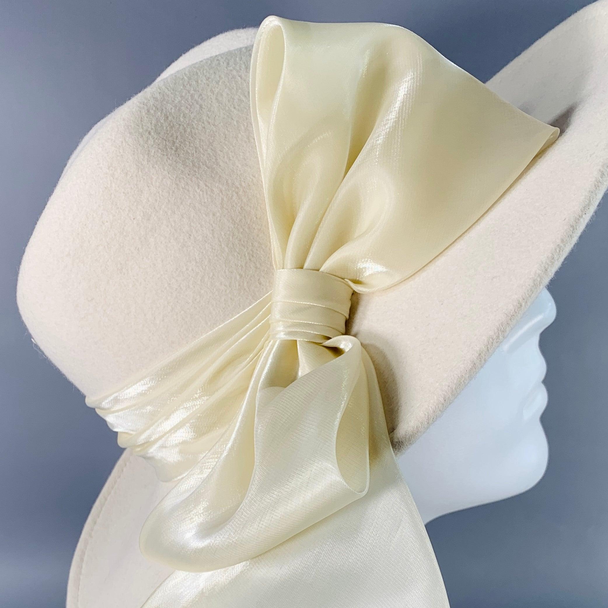 EUGENIA KIM fedora
in a white wool felt featuring wide brim and large dramatic bow trim. Made in USA.Very Good Pre-Owned Condition. Multiple minor marks on underside of hat. 

Measurements: 
  Opening: 23 inches Brim: 3.5 inches Height: 5 inches 
 