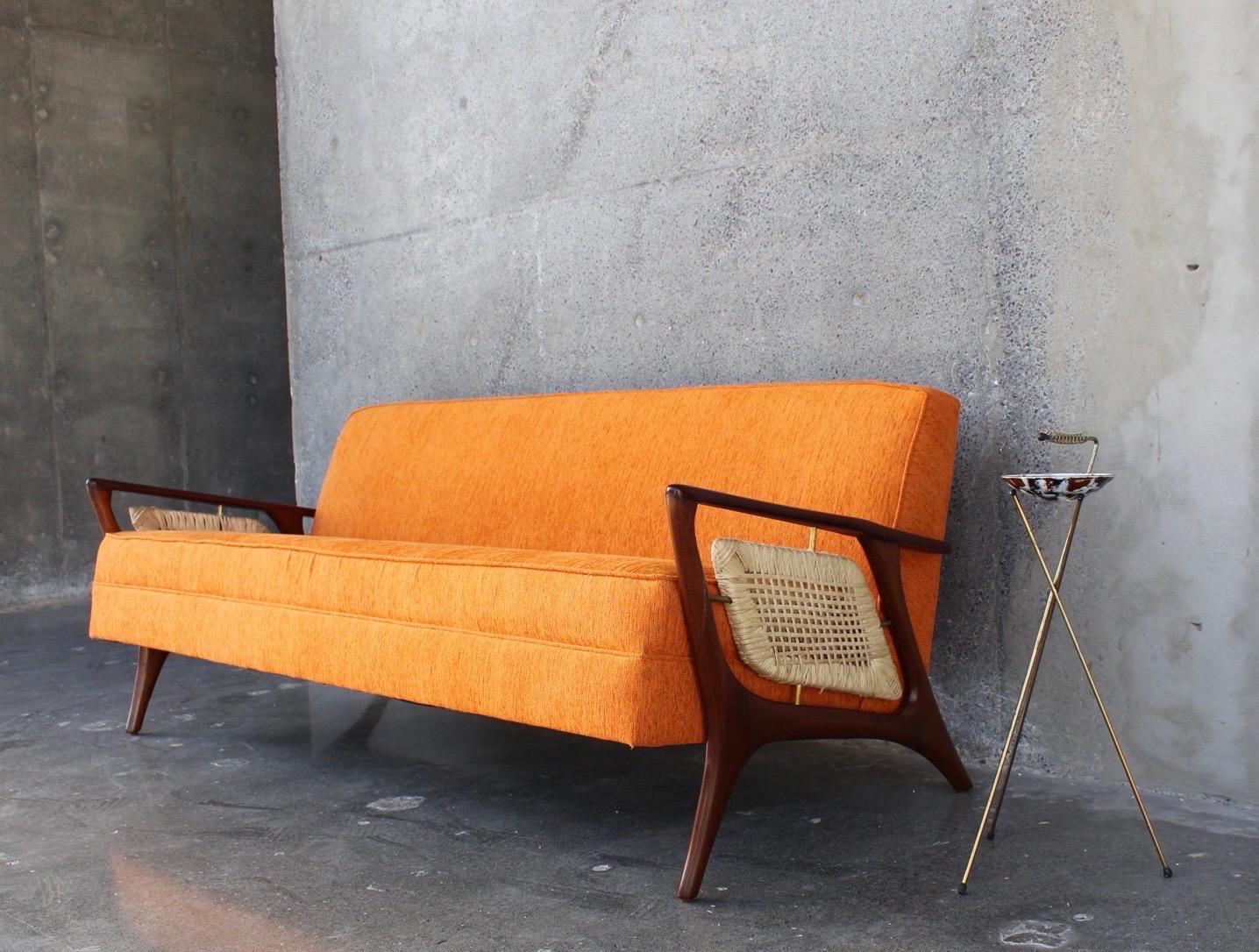 The sofa's sculptural design done by Eugenio Escudero of the late 1950s. The sofa was made in mahogany and professionally restored, Escudero is cataloged one of the greatest icons of Mexican modernism.