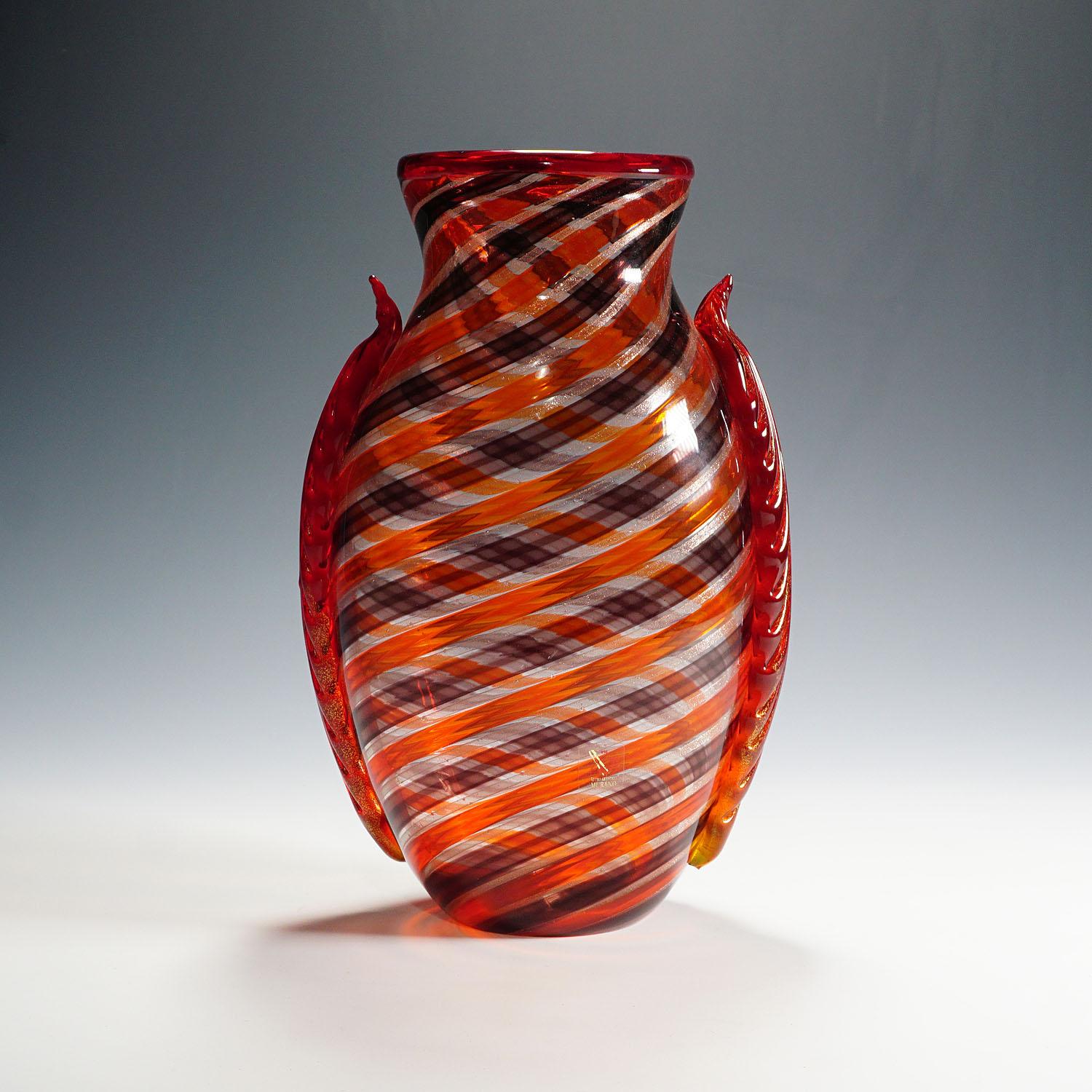 A large Murano art glass vase, designed and made by Eugenio Ferro & C. 1929 srl in 2009. Thick clear glass with spiral pattern in orange, aubergine and aventurine. Two lateral applications made of orange glass with some gold inclusions. Vetro