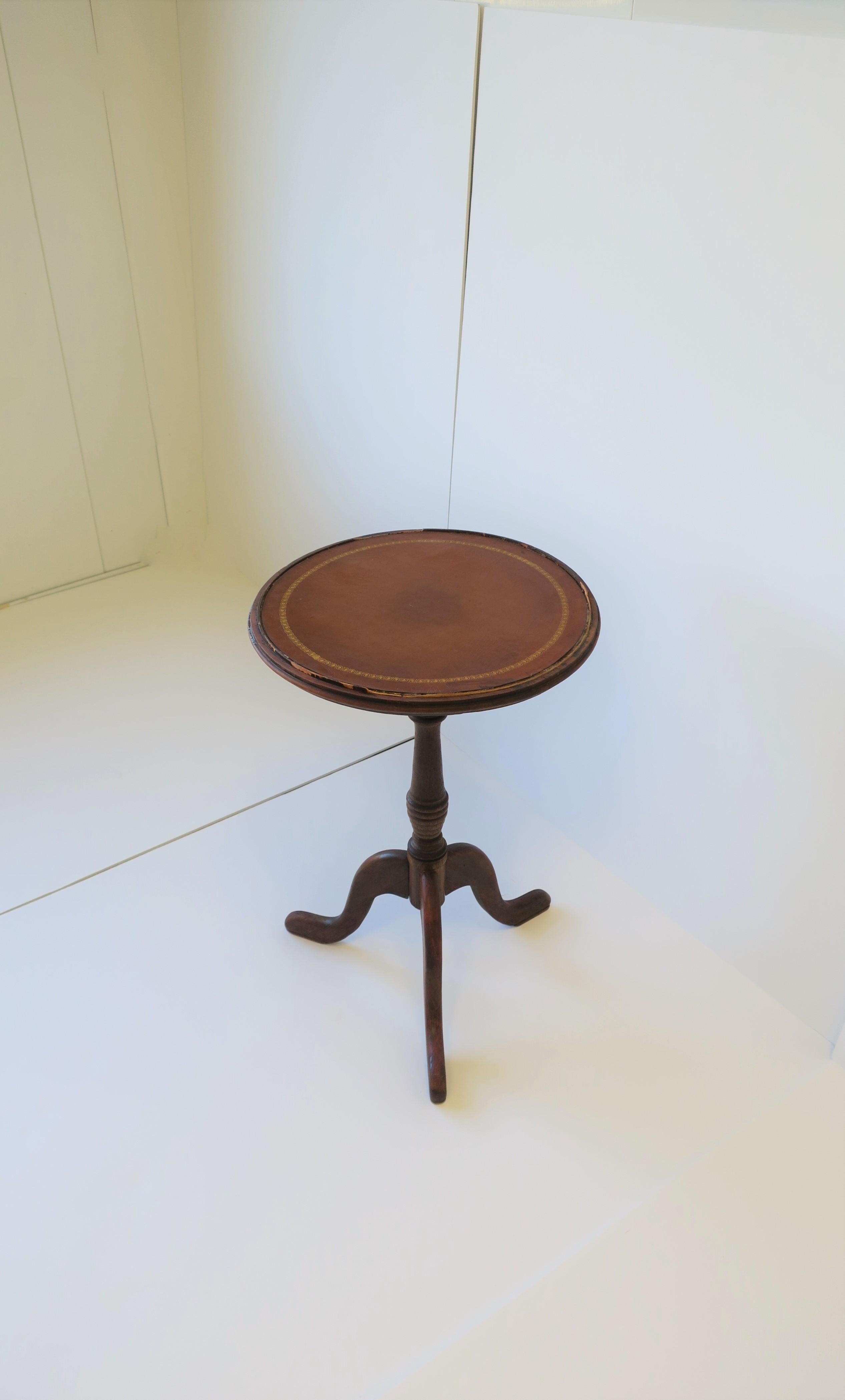 A European tripod leather and wood side or drinks table, circa mid-20th century, Europe (probably England, but maybe France.) Table has a honey brown leather top with gold edge embossed detailing, and a tripod wood base. 

Table measures: 14