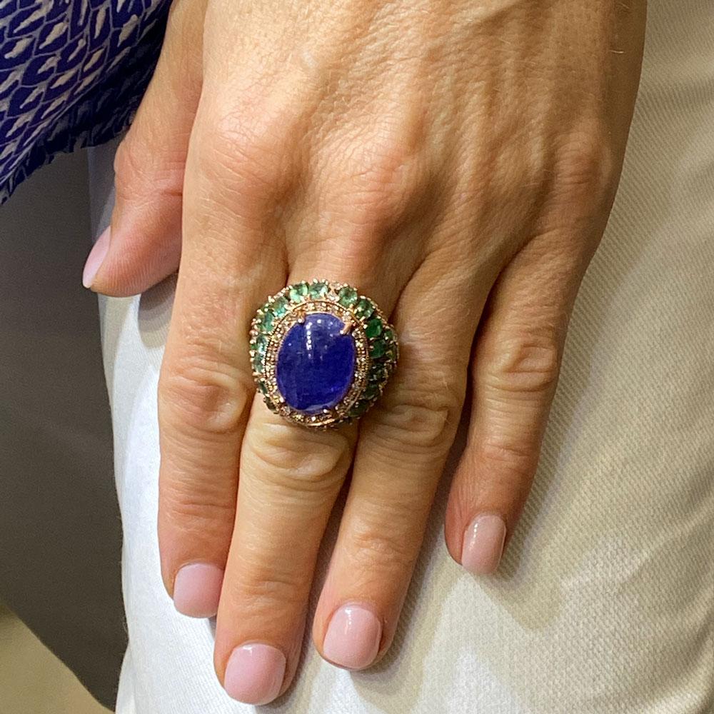Fabulous Tanzanite, Emerald, and Diamond Cocktail Ring. Fashioned in 9 karat rose gold ring, the ring features a 15 carat cabochon tanzanite gemstone surrounded with diamonds and emeralds. Eight carats of emeralds and 1.04 carats of diamonds are