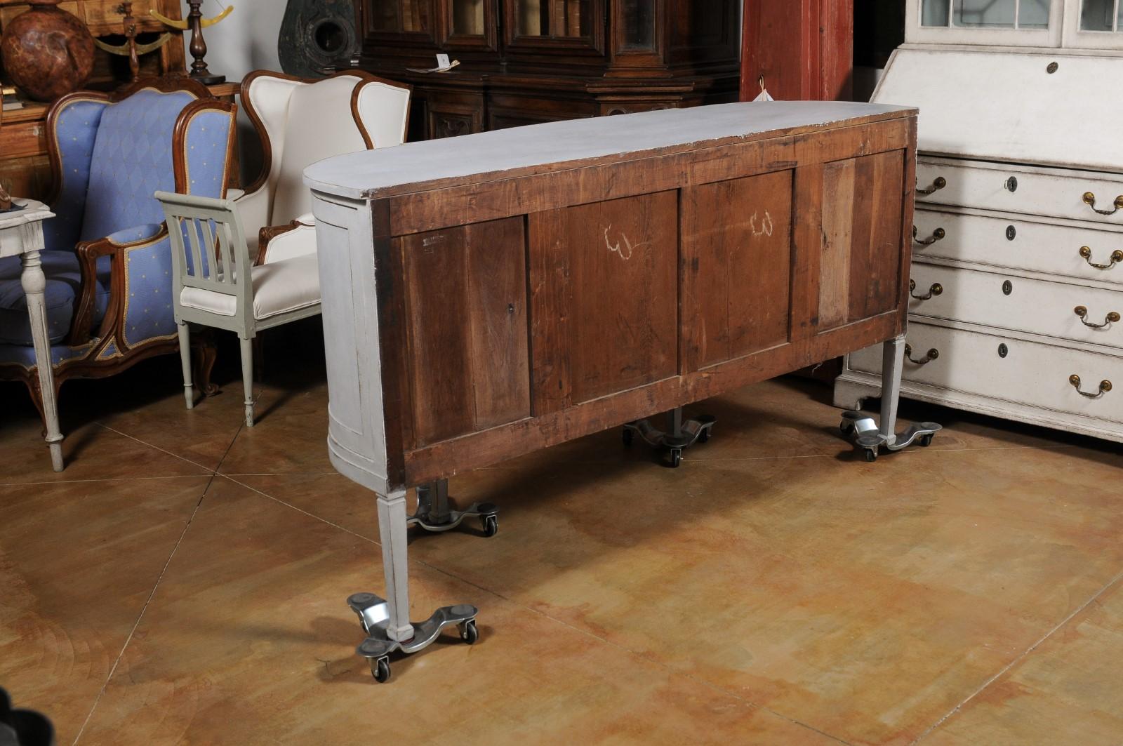 A European painted demillune sideboard from the early 19th century, with three drawers and rounded doors. Created in Europe during the second quarter of the 19th century, this painted sideboard features a semi-circular top with protruding front,