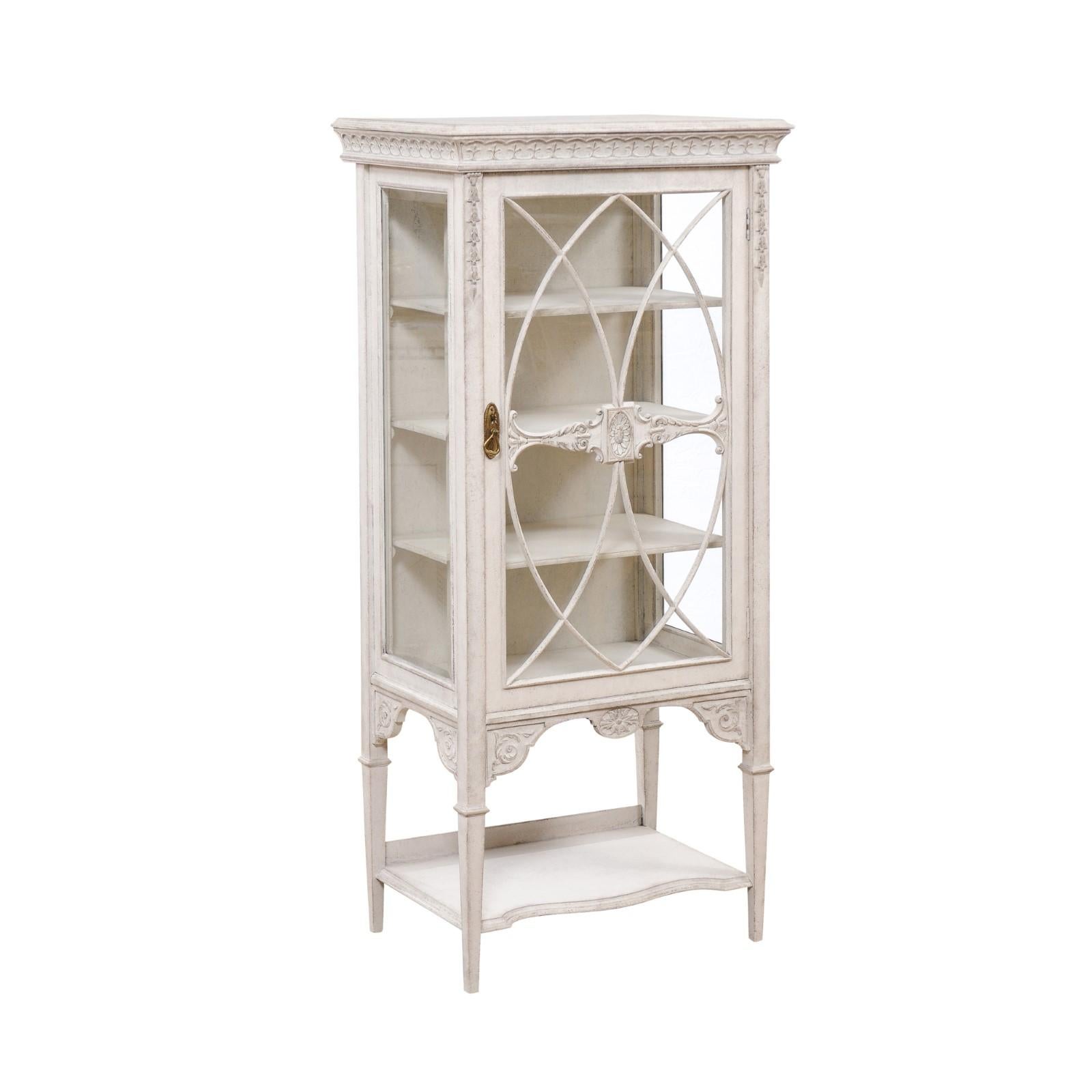 A European painted wood vitrine cabinet from the late 19th century, with richly carved décor, glass doors and lower shelf. Created on the Continent during the last decade of the 19th century, this elegant vitrine cabinet features a beveled cornice