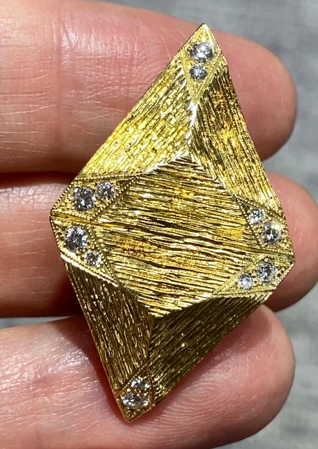 These striking 1970s 18k gold earrings are hand made and hand engraved. The corners of each triangular piece is adorned with small diamonds which accentuate the overall sparkle of the earrings. 

The earrings are a part of a set with a bracelet and
