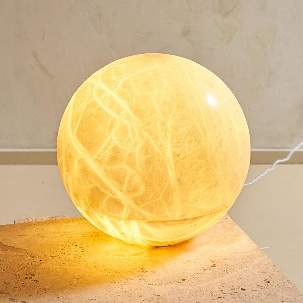 A vintage 1970s Globular lamp formed of carved alabaster stone. Alabaster is a semi precious stone which means light can pass through it; this lamp emits a warm ambient, some may even say, romantic glow. The top 3/4 of the sphere rests on the base;